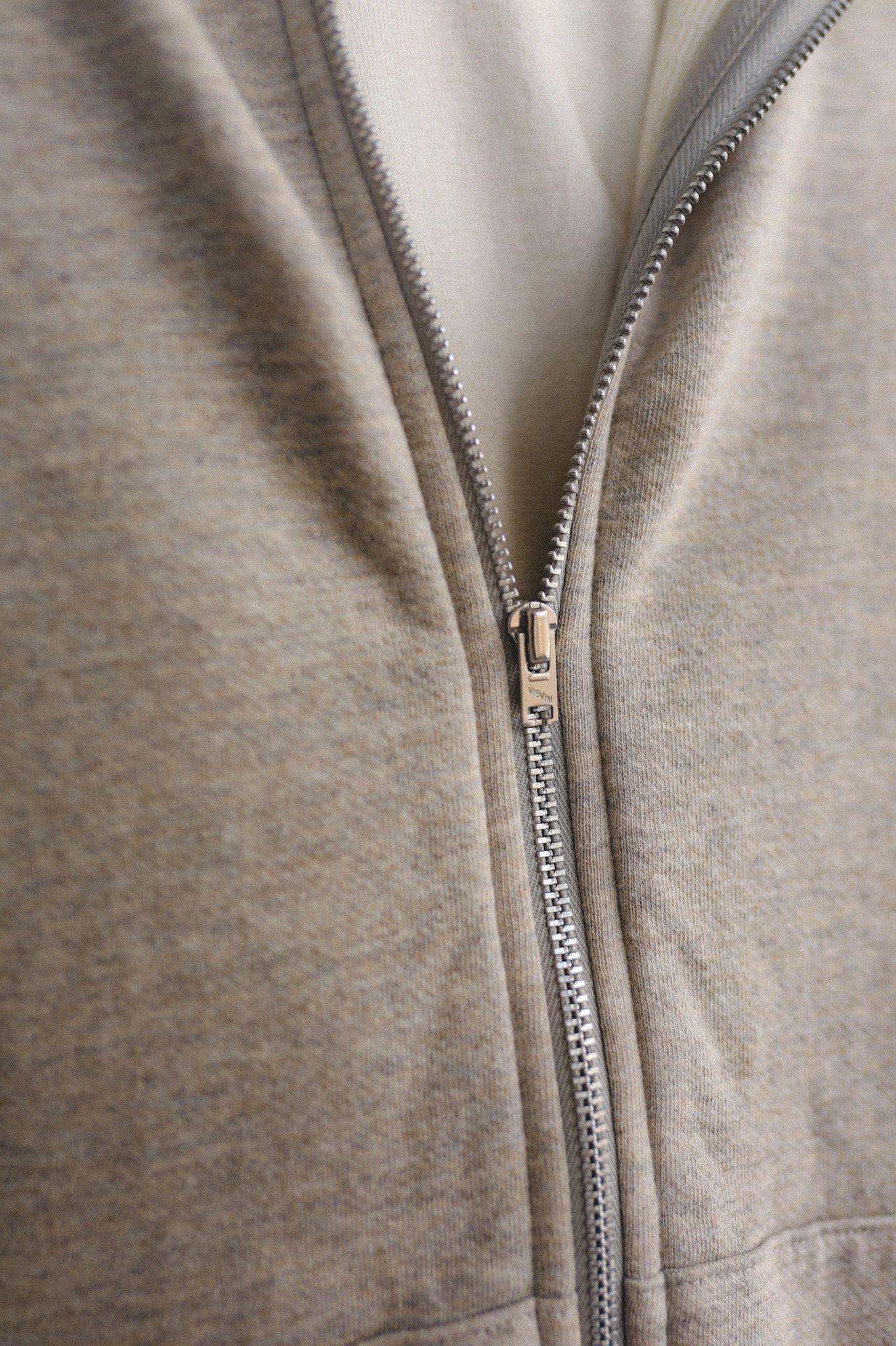 Close-up of a gray zip-up hoodie with a zipper detail.