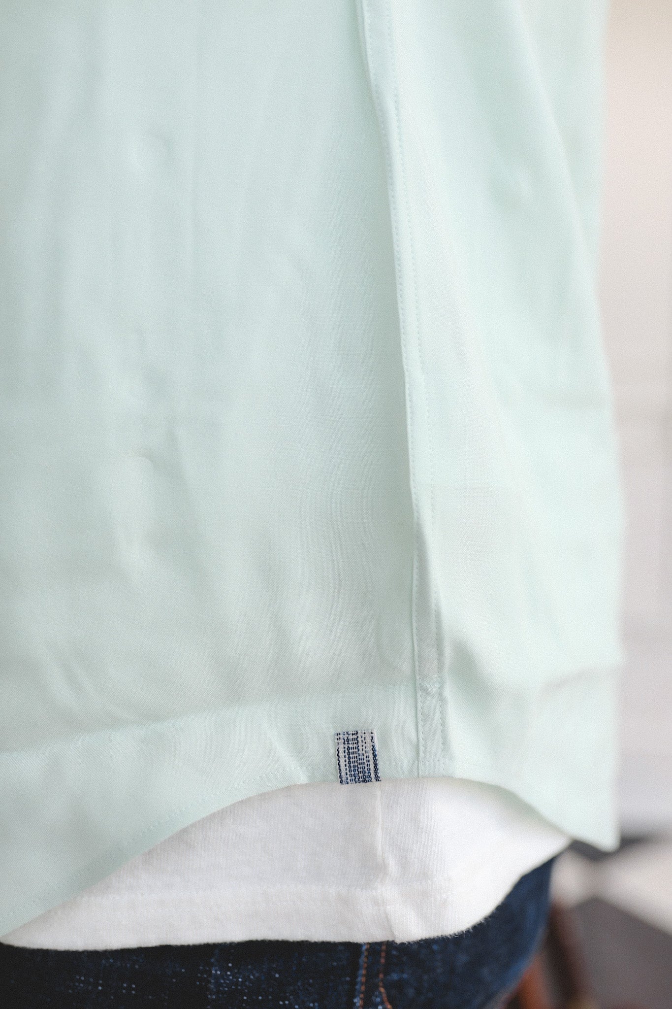 Close-up of a light green shirt collar with a brand label.