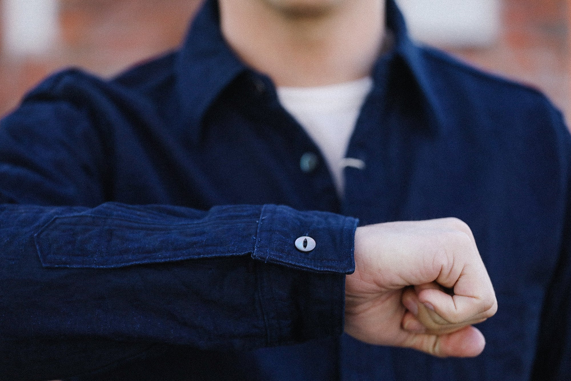 Person wearing a navy blue shirt with rolled-up sleeve, blurred background