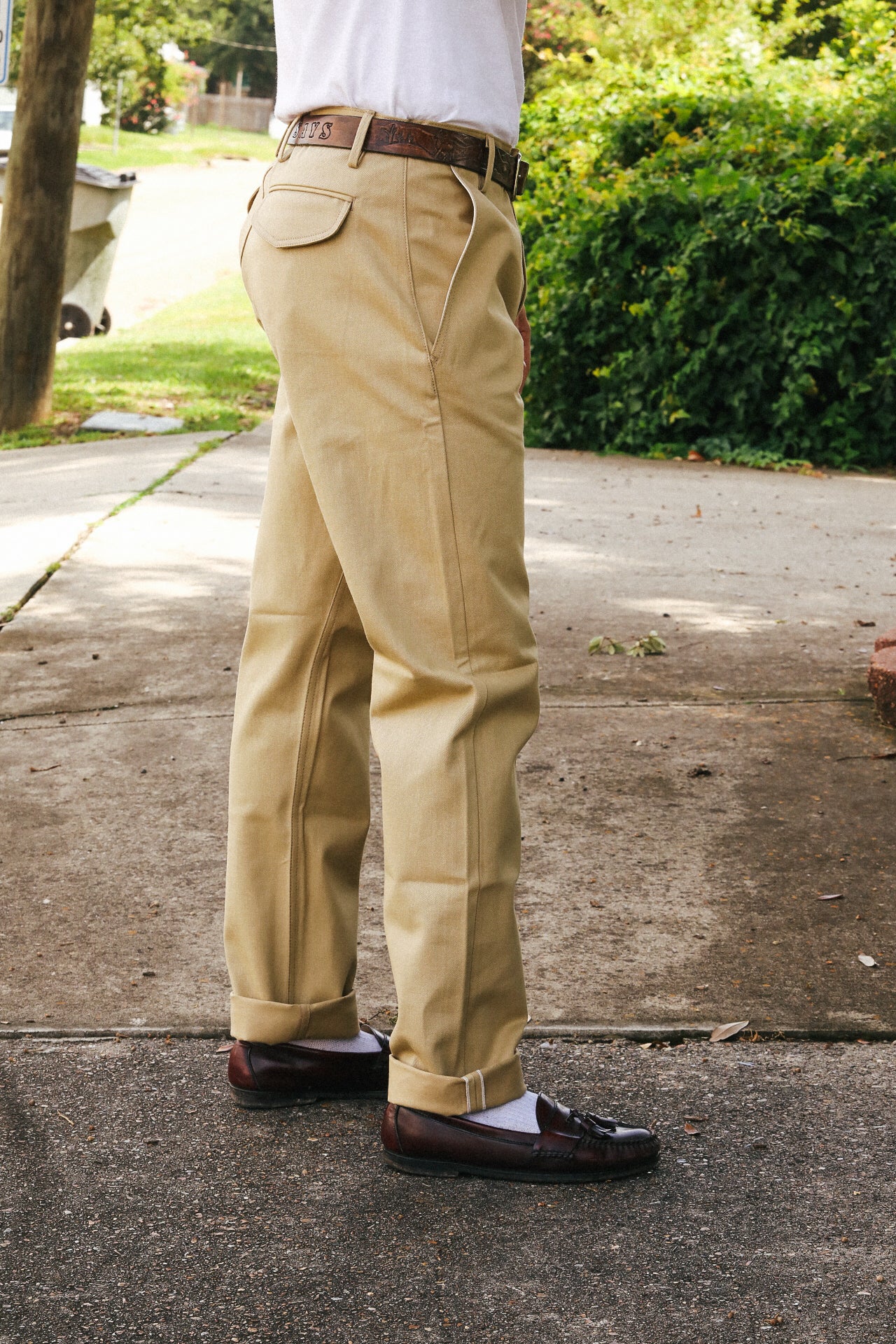 Side view of person wearing tan work pants with leather belt and brown leather loafers outdoors