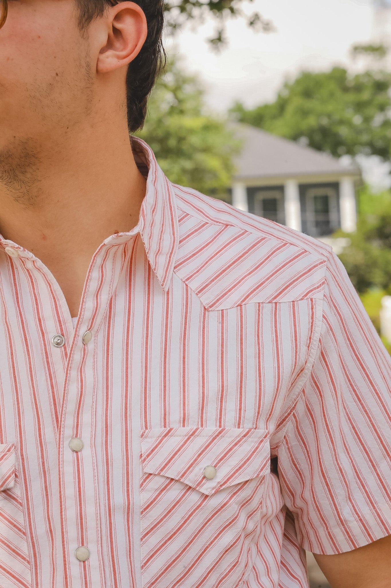 Close-up of a person wearing a red and white striped shirt with a blurred background