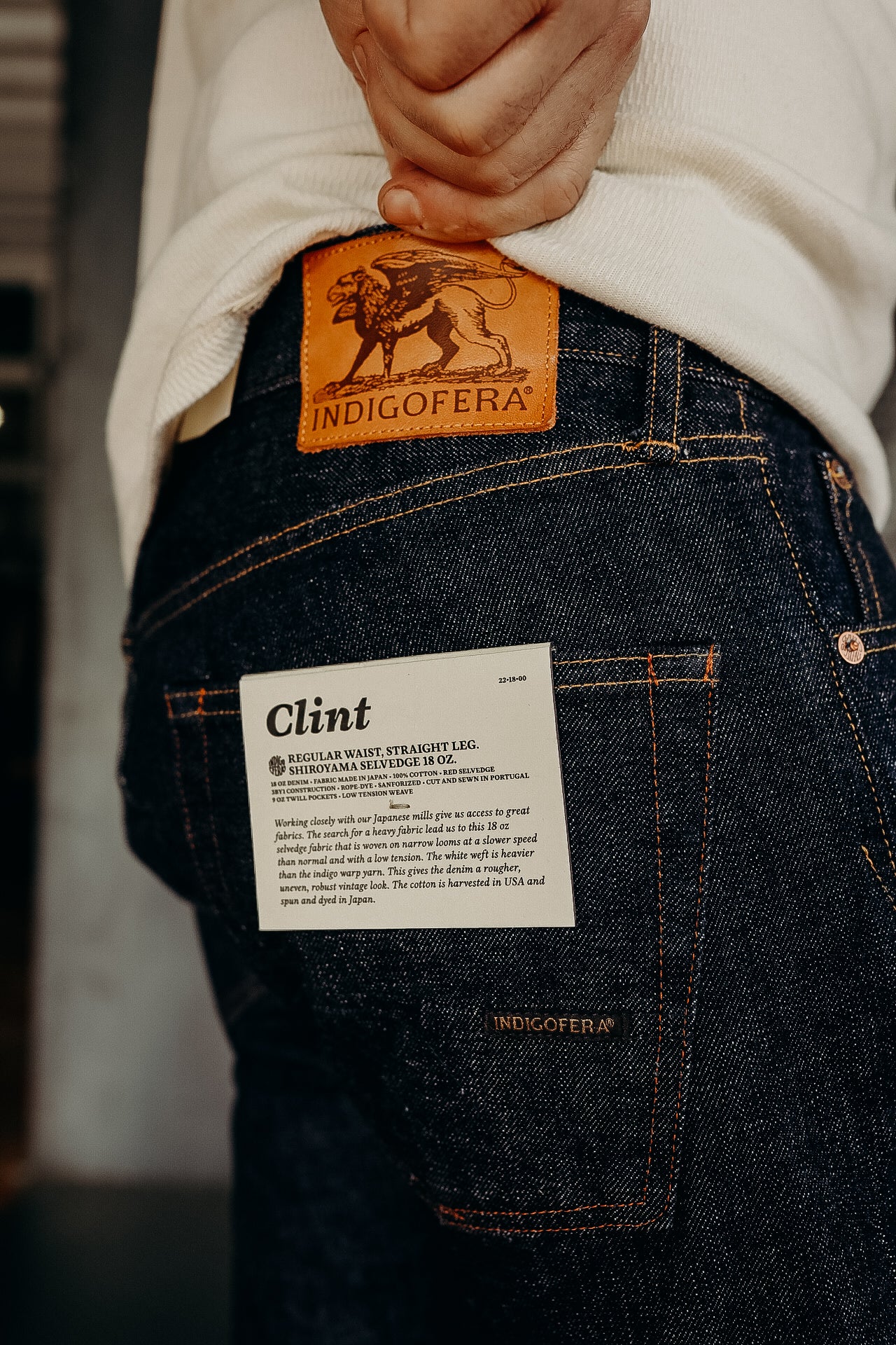 Person wearing Indigofera Clint 18 oz heavy selvedge denim jeans with leather brand patch and product label