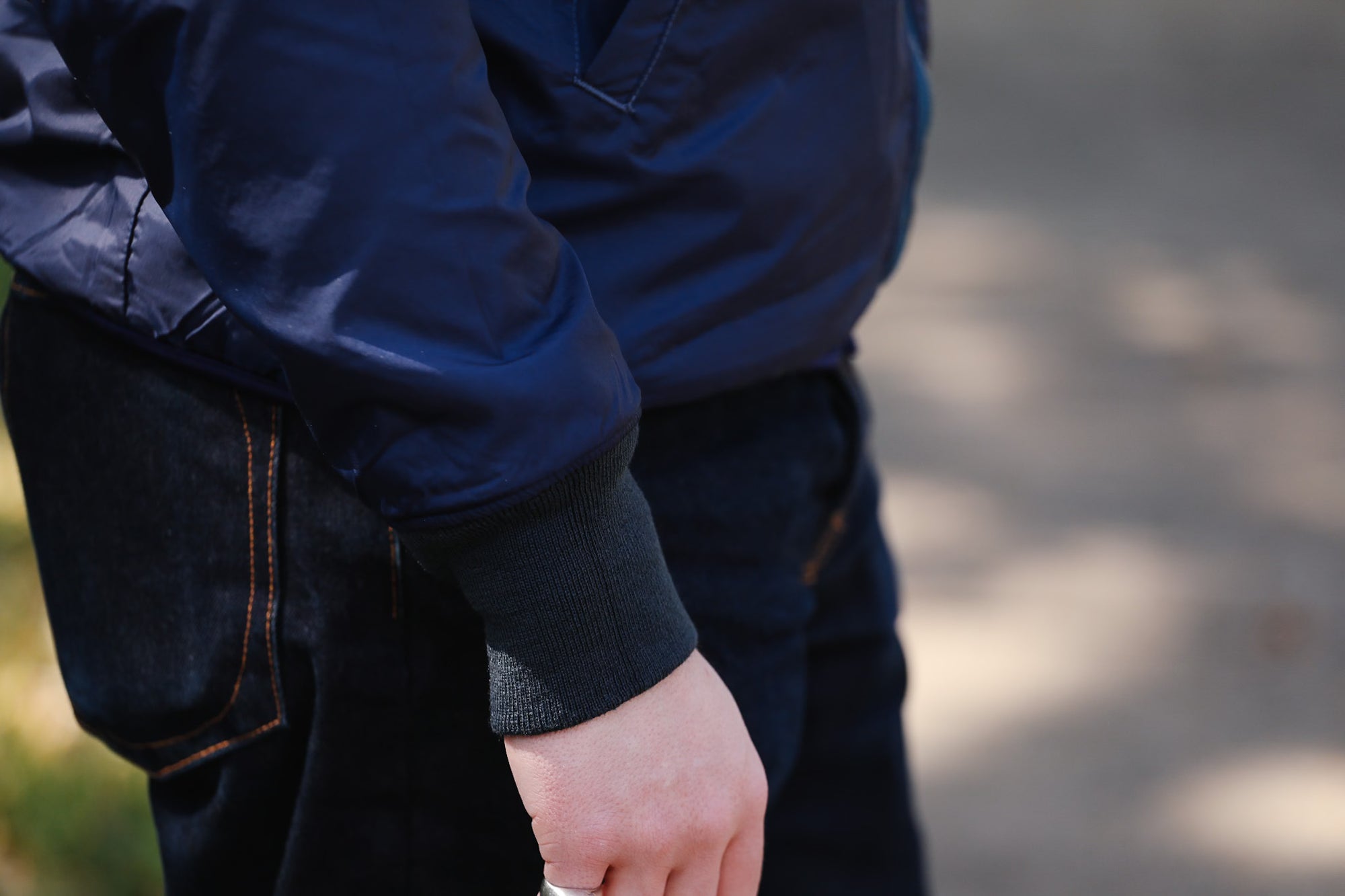 Person wearing a blue jacket and dark pants with a blurred background