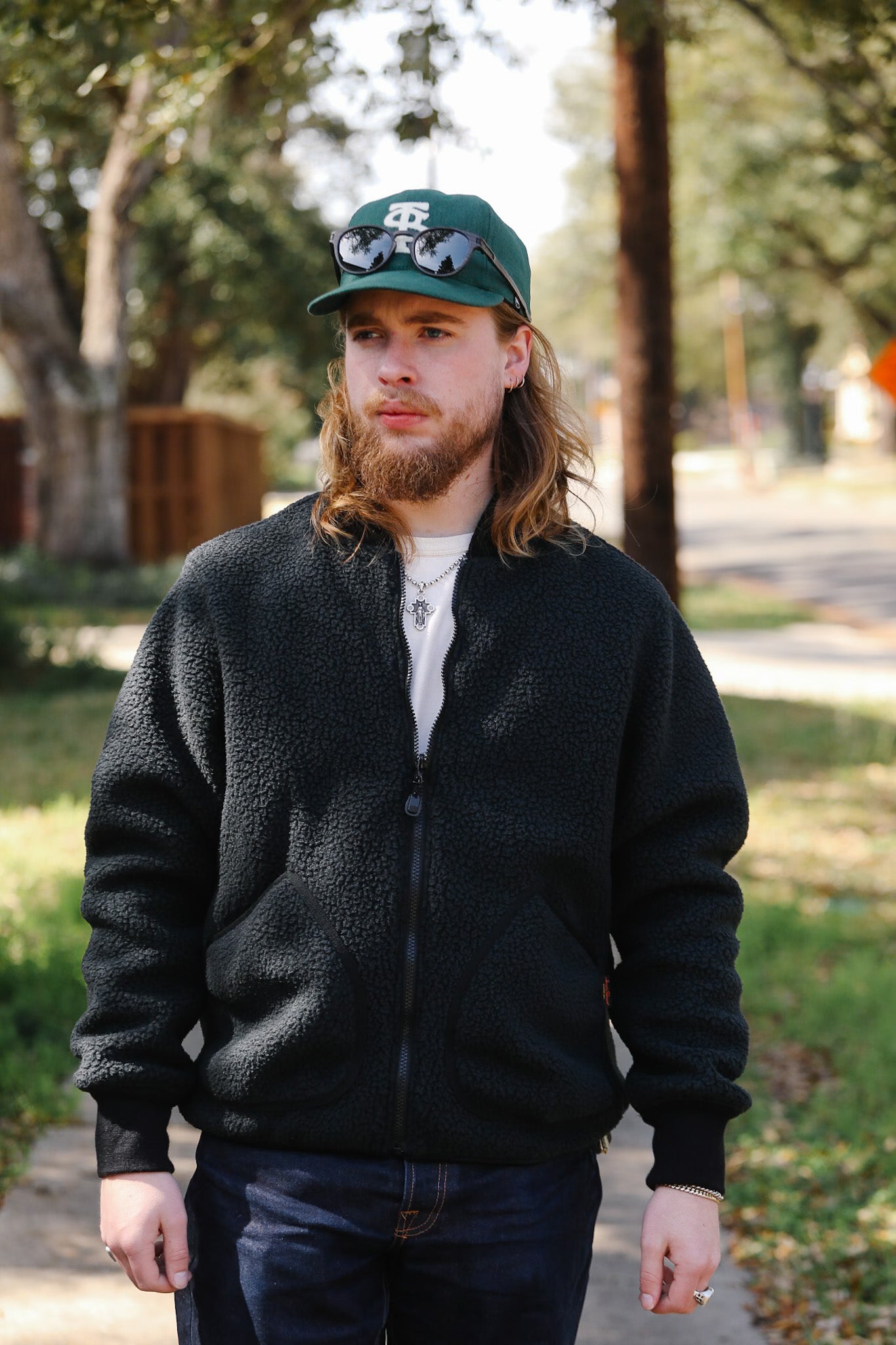 Man wearing a black jacket and green cap outdoors