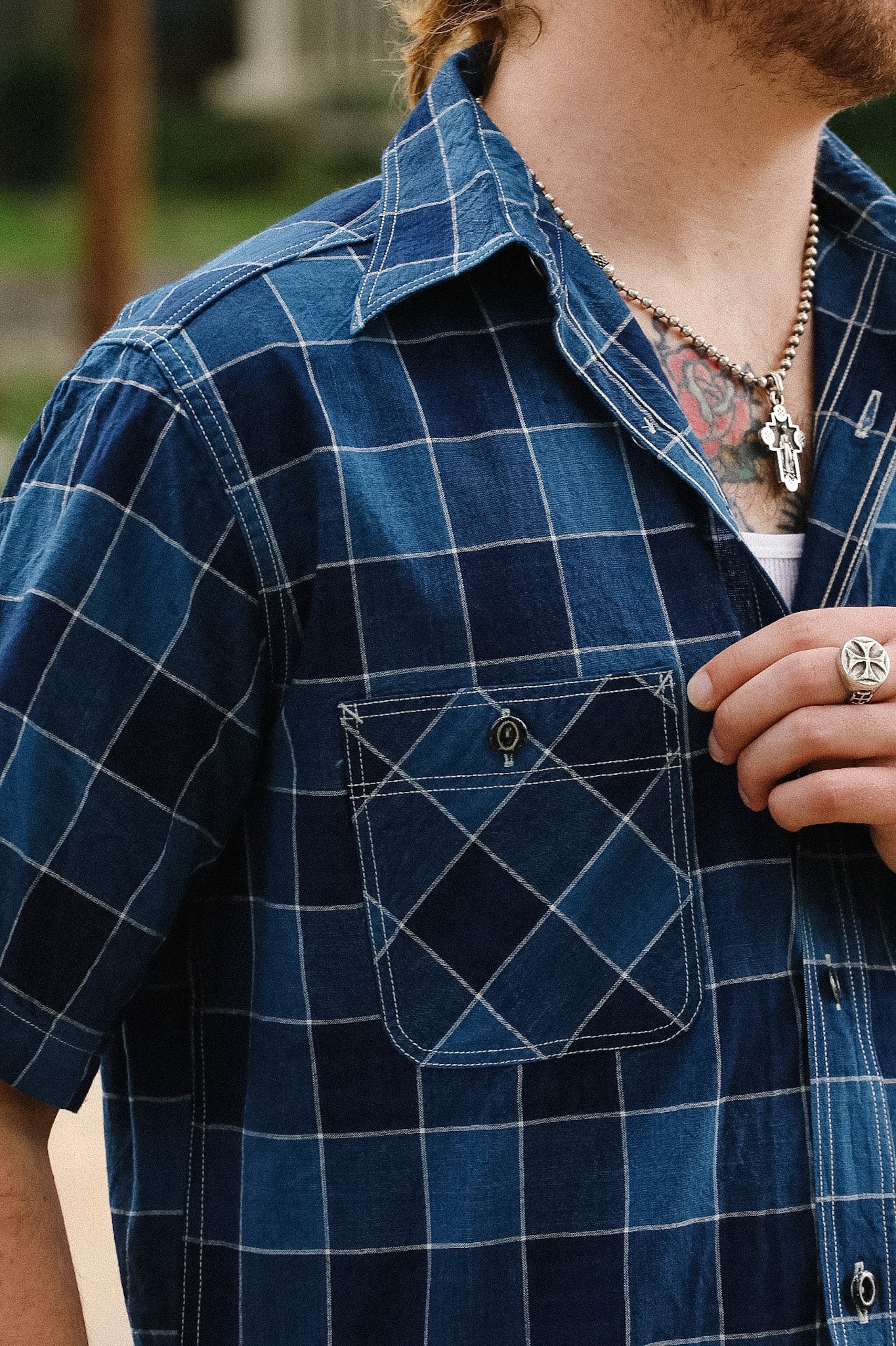 Person wearing a blue plaid shirt with a focus on the chest pocket.