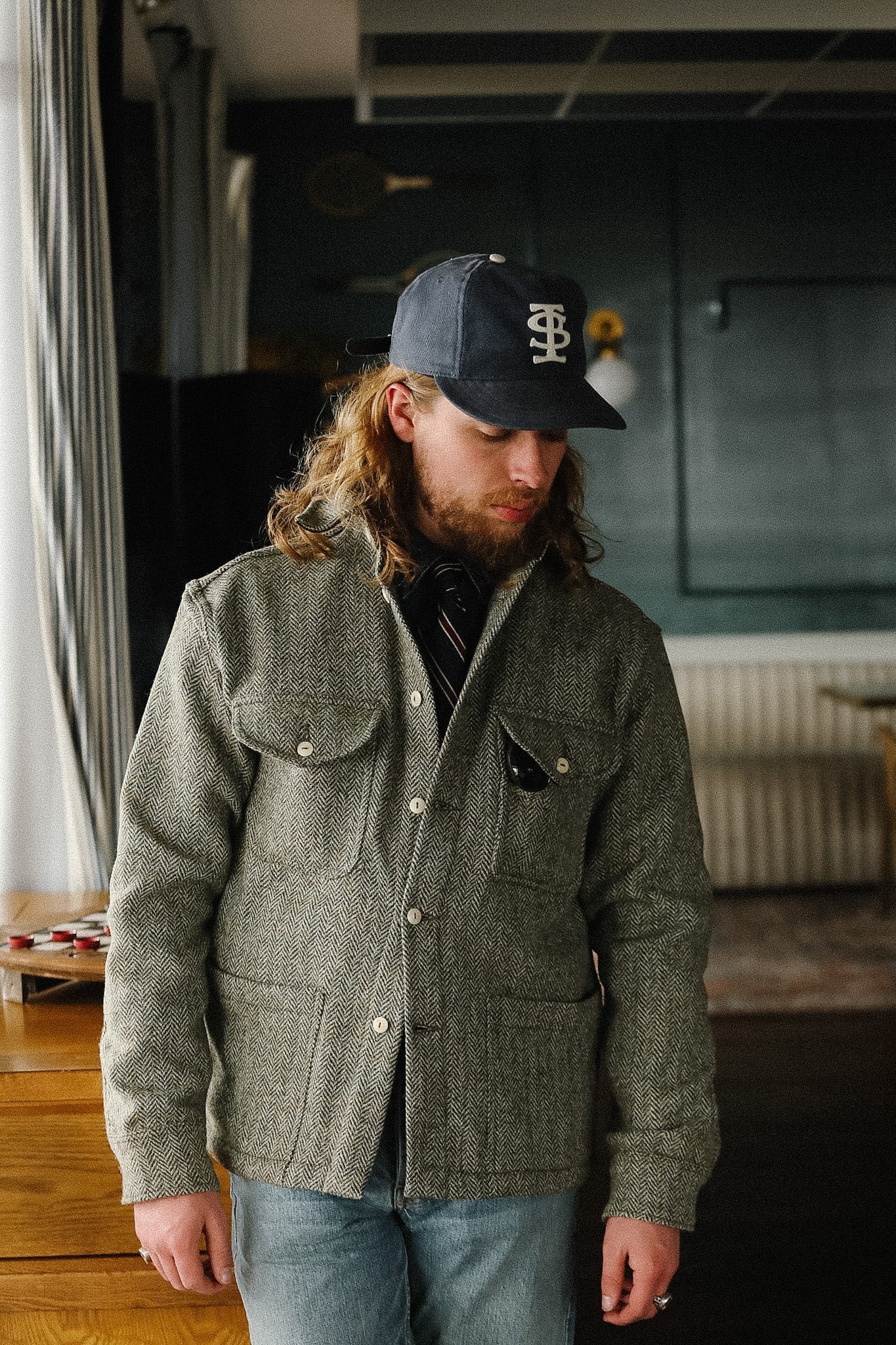 Man wearing a green jacket and cap indoors