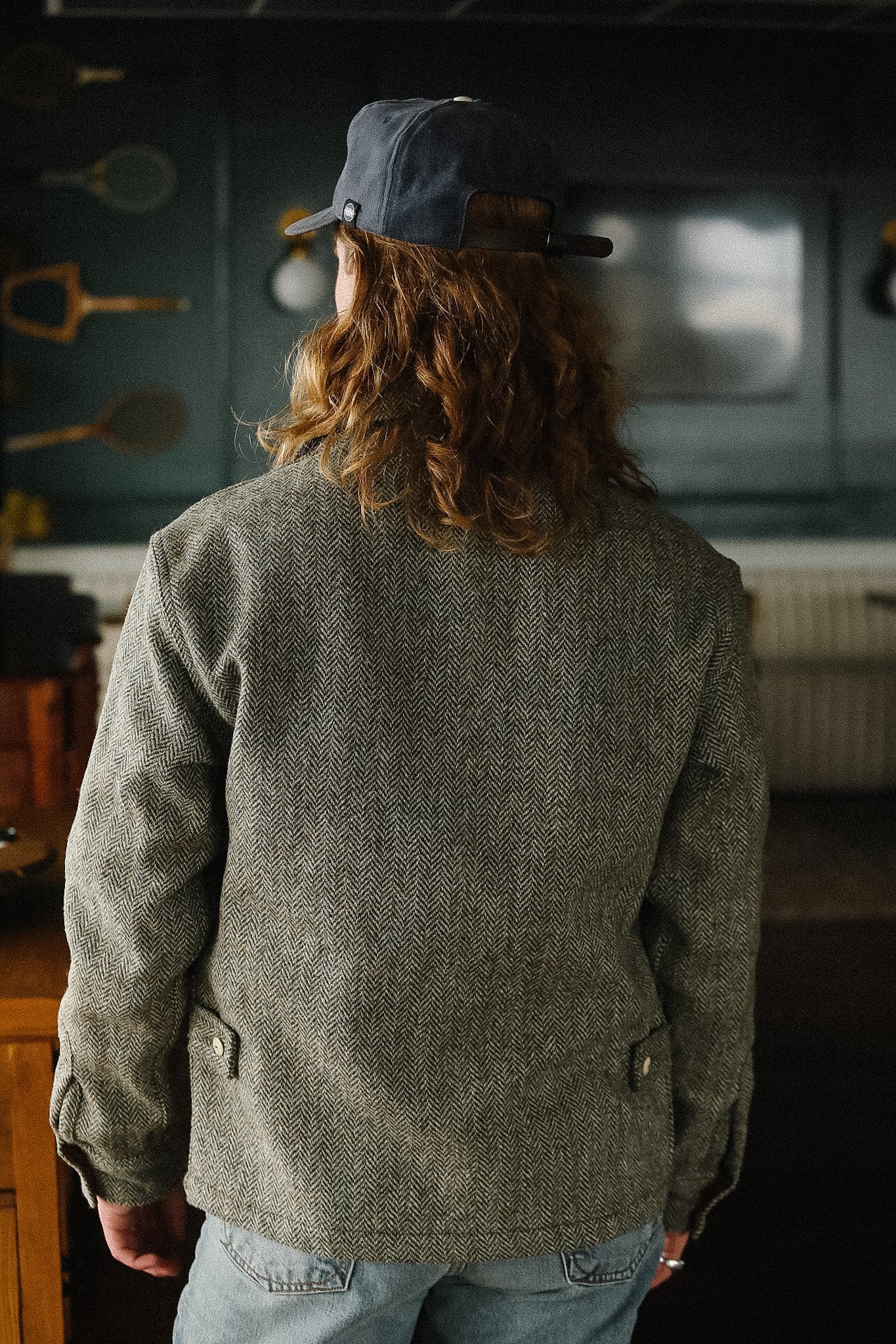 Person wearing a green jacket and blue cap in a kitchen setting