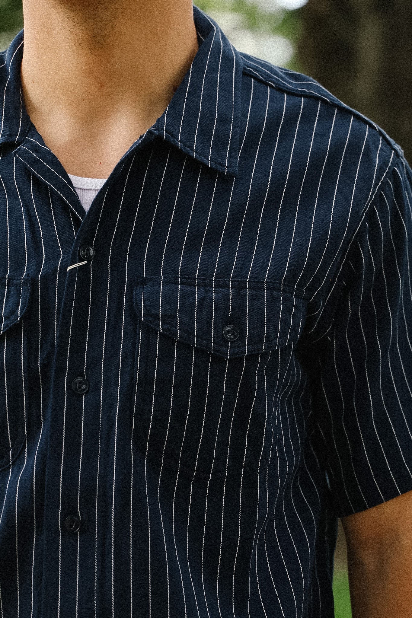 Close-up of a person wearing a navy blue pinstripe shirt.
