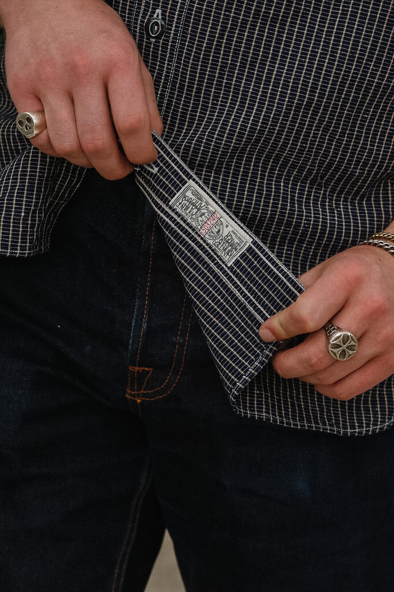 Person holding a knife with a checkered shirt and dark pants