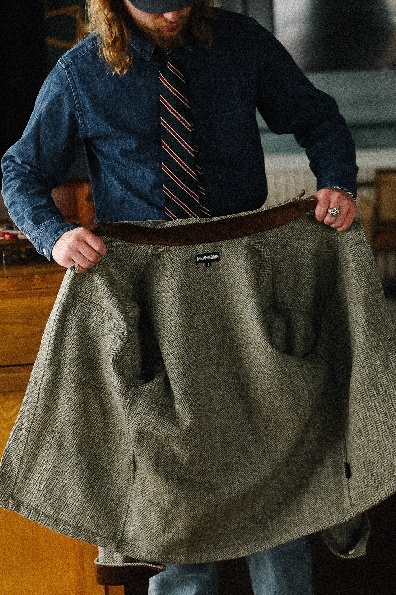 Person holding a gray coat with a visible brand logo in an indoor setting