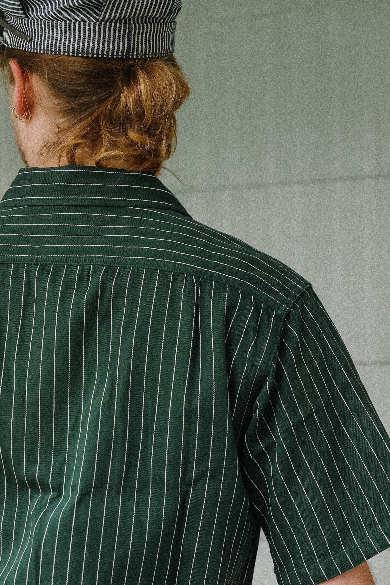 Person wearing a green pinstripe shirt and striped hat in a kitchen setting