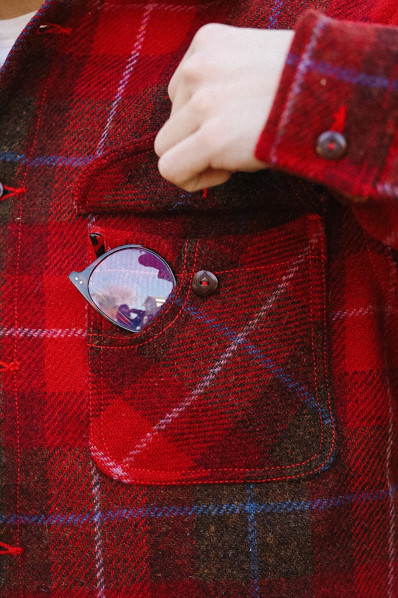 Red plaid jacket with a pocket containing sunglasses