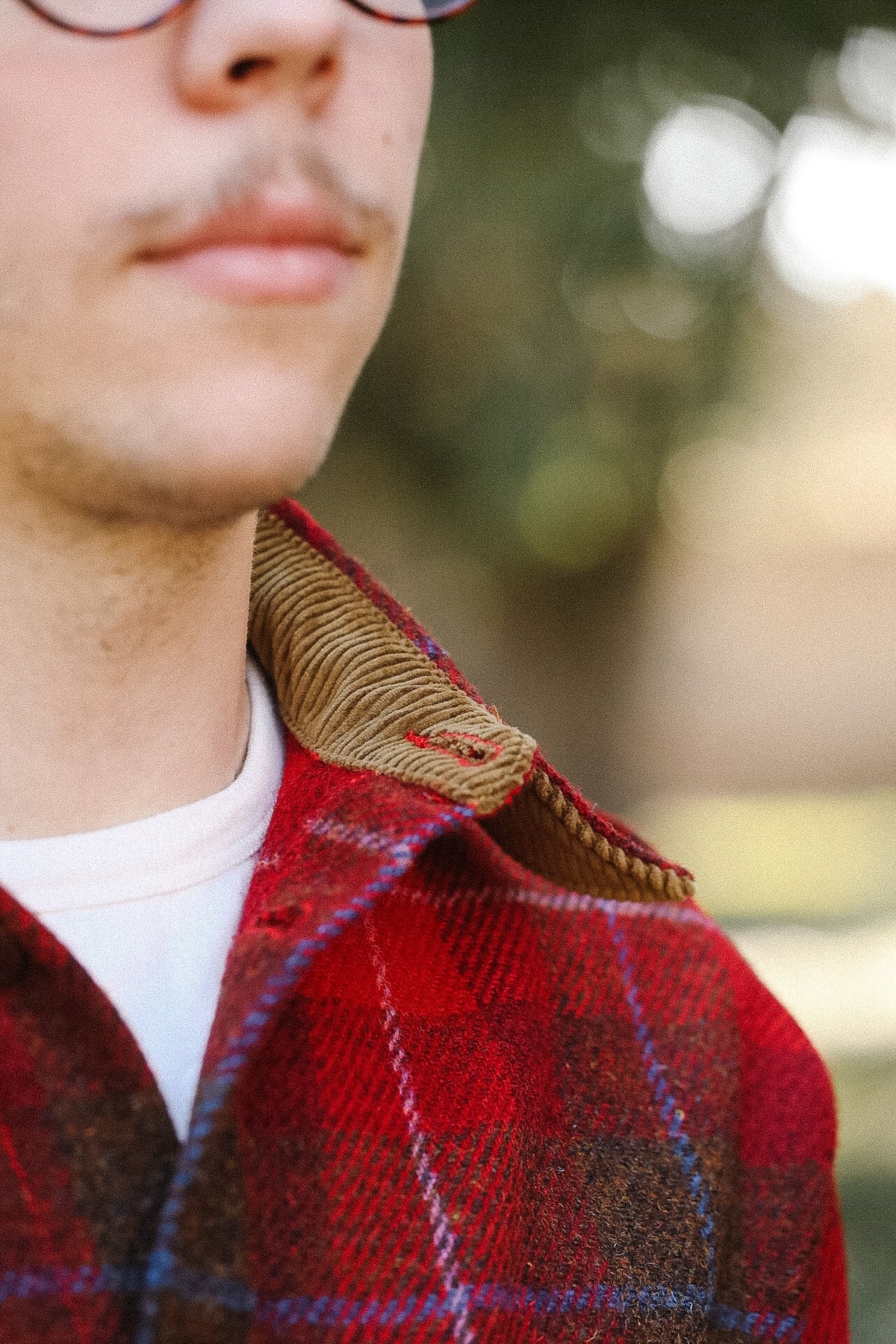 Close-up of a person wearing a red plaid jacket with a blurred outdoor background