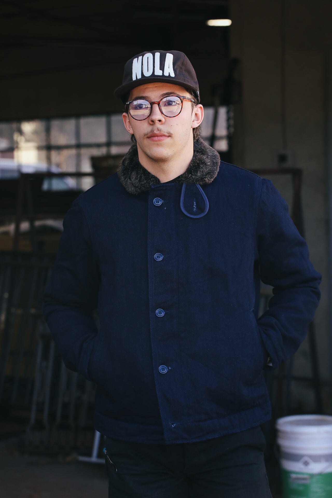 man wearing blue denim UES deck jacket and standing in front of windows 