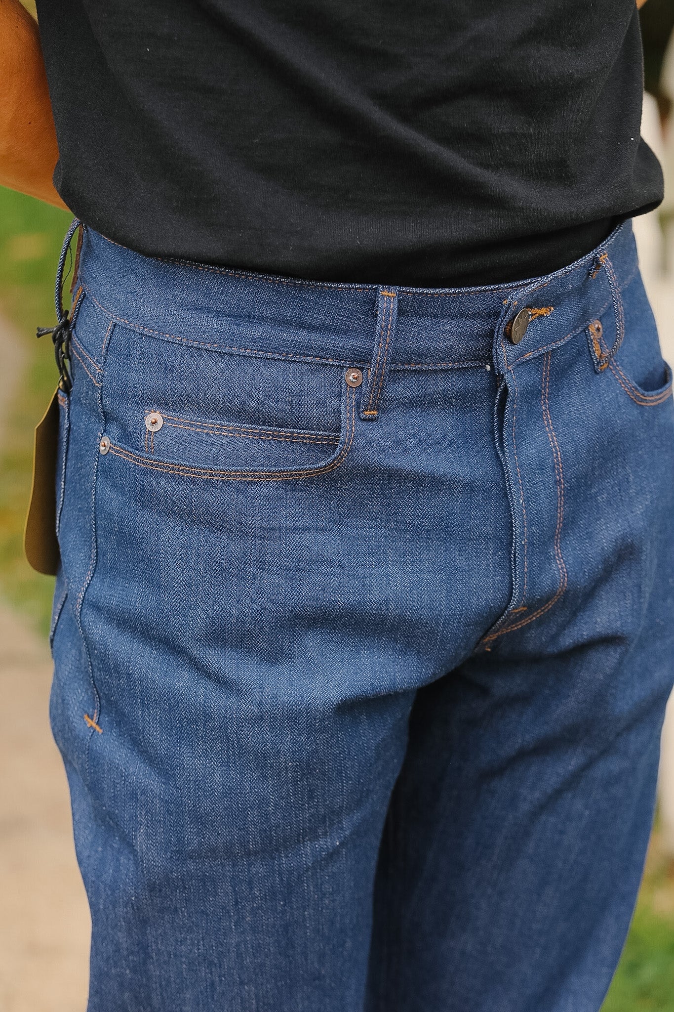 Close-up of blue jeans worn by a person with a blurred background