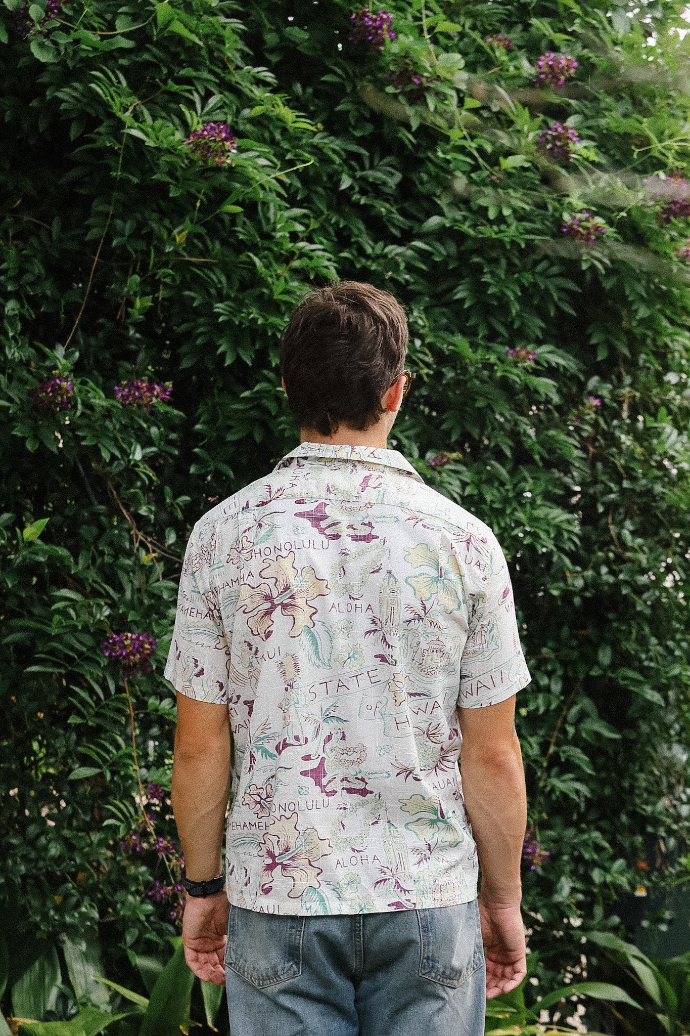 Person wearing a floral shirt standing in front of a green leafy background