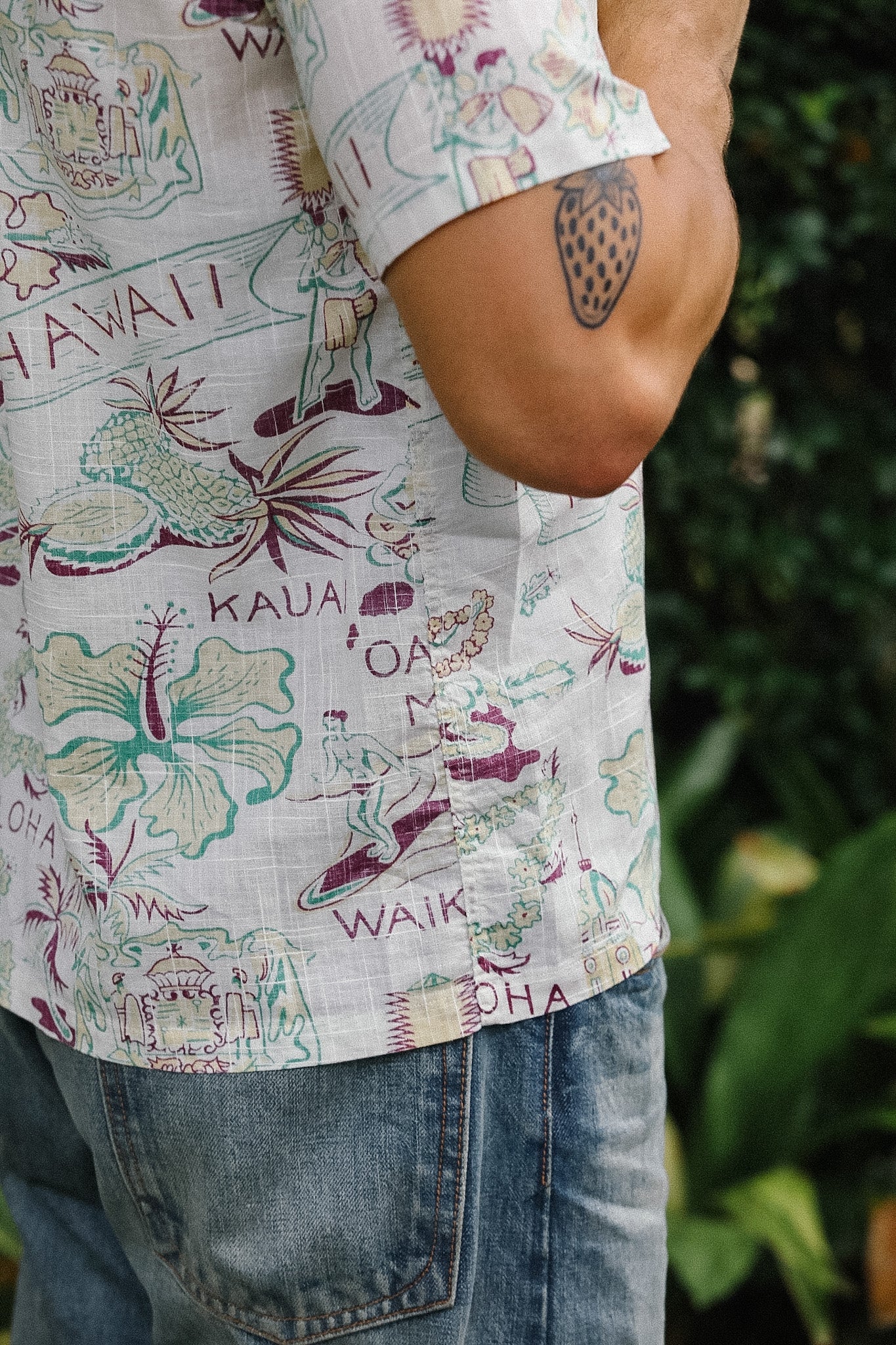 Person wearing a colorful shirt with Hawaiian-themed designs and text.