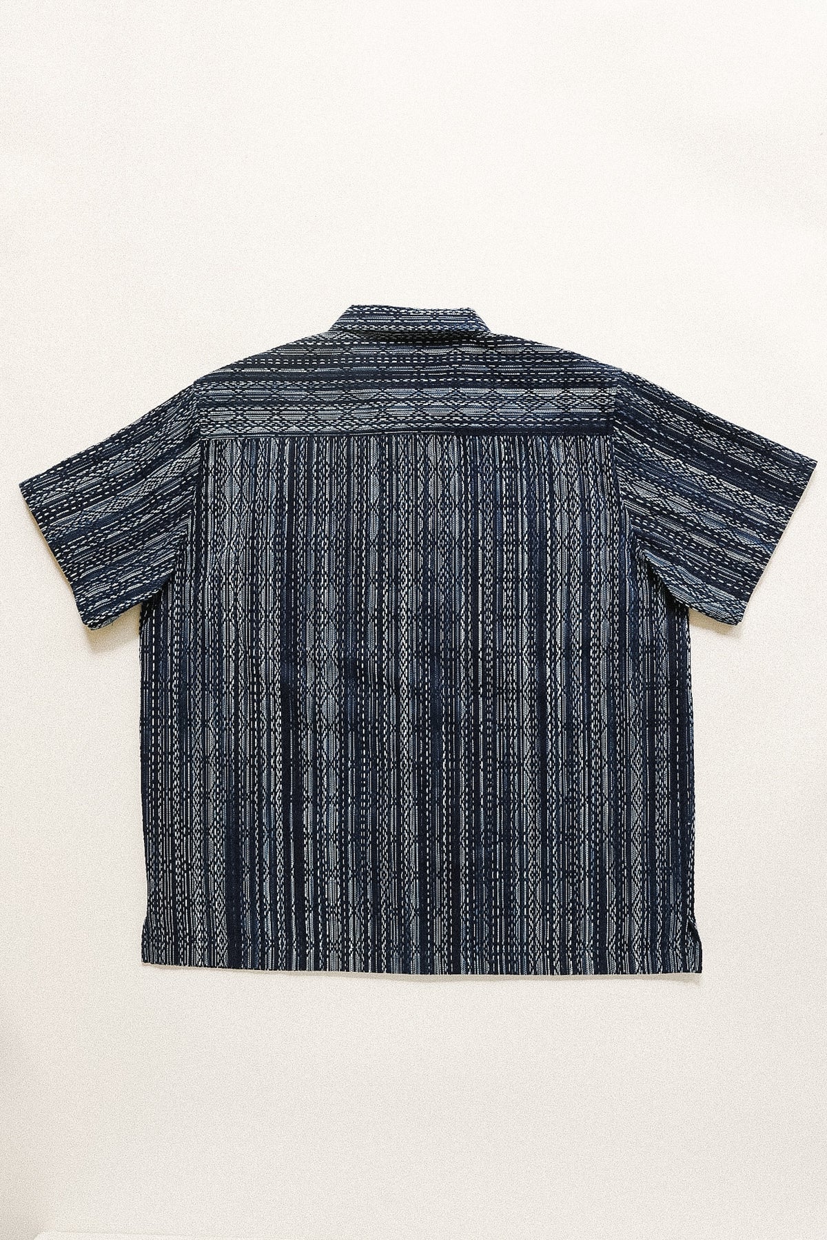 Back view of a dark blue patterned shirt on a white background