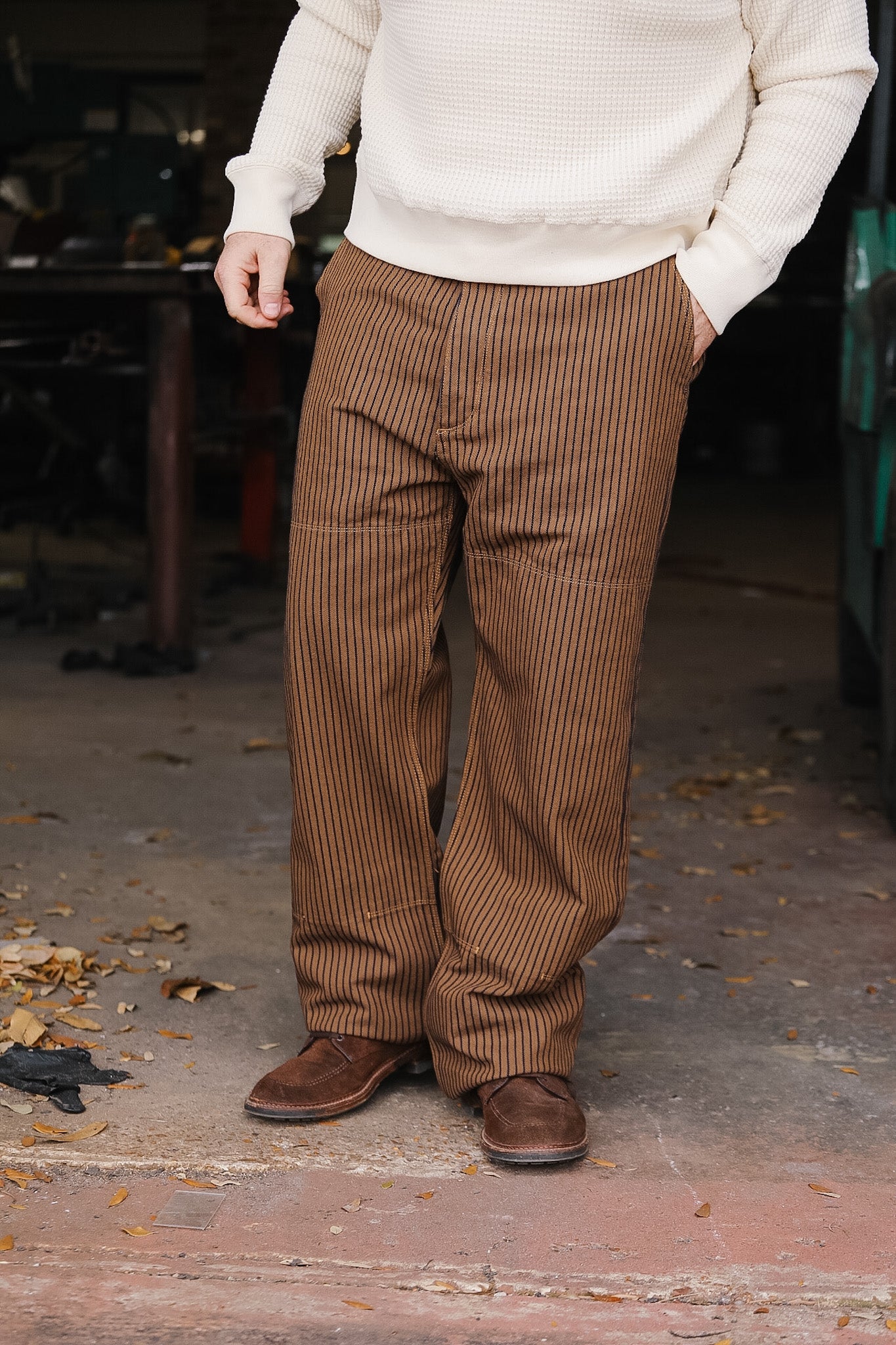 Person wearing brown striped pants and a white sweater in an outdoor setting