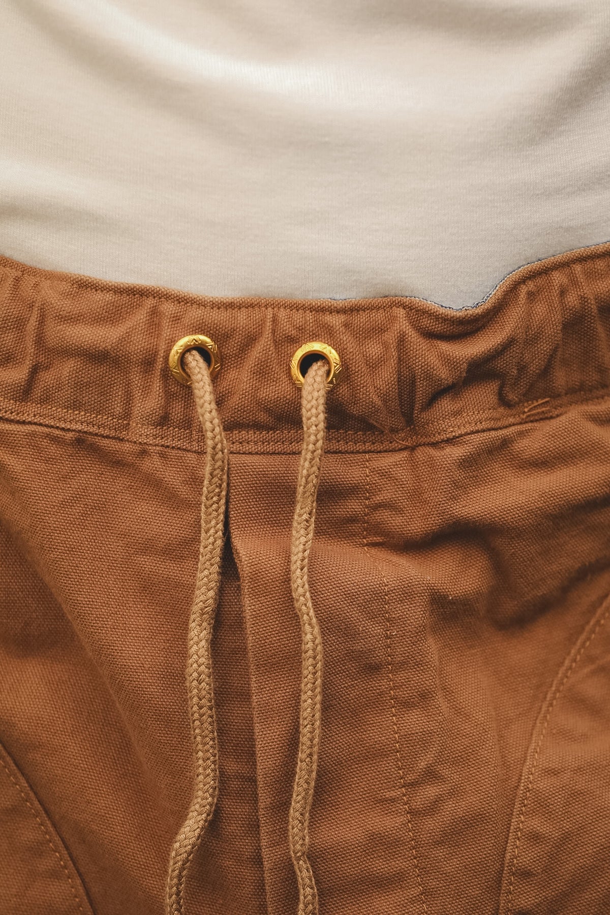 Close-up of brown pants with drawstring and beige shirt in the background