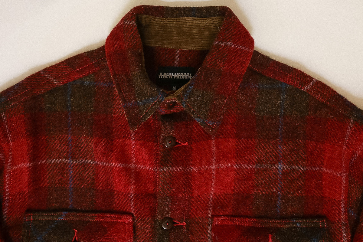 Red and black plaid jacket with a visible brand label on a white background