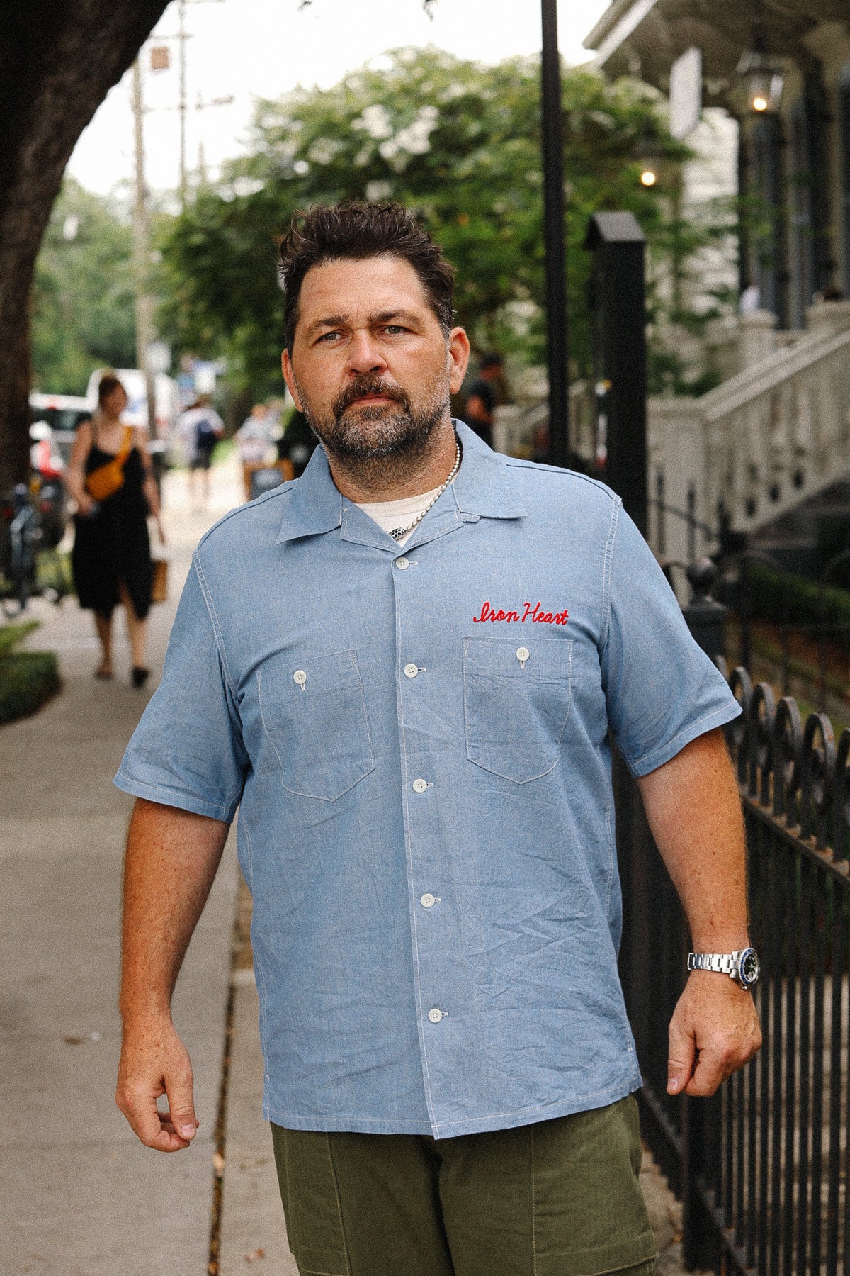 Man wearing a blue shirt with text on a sidewalk