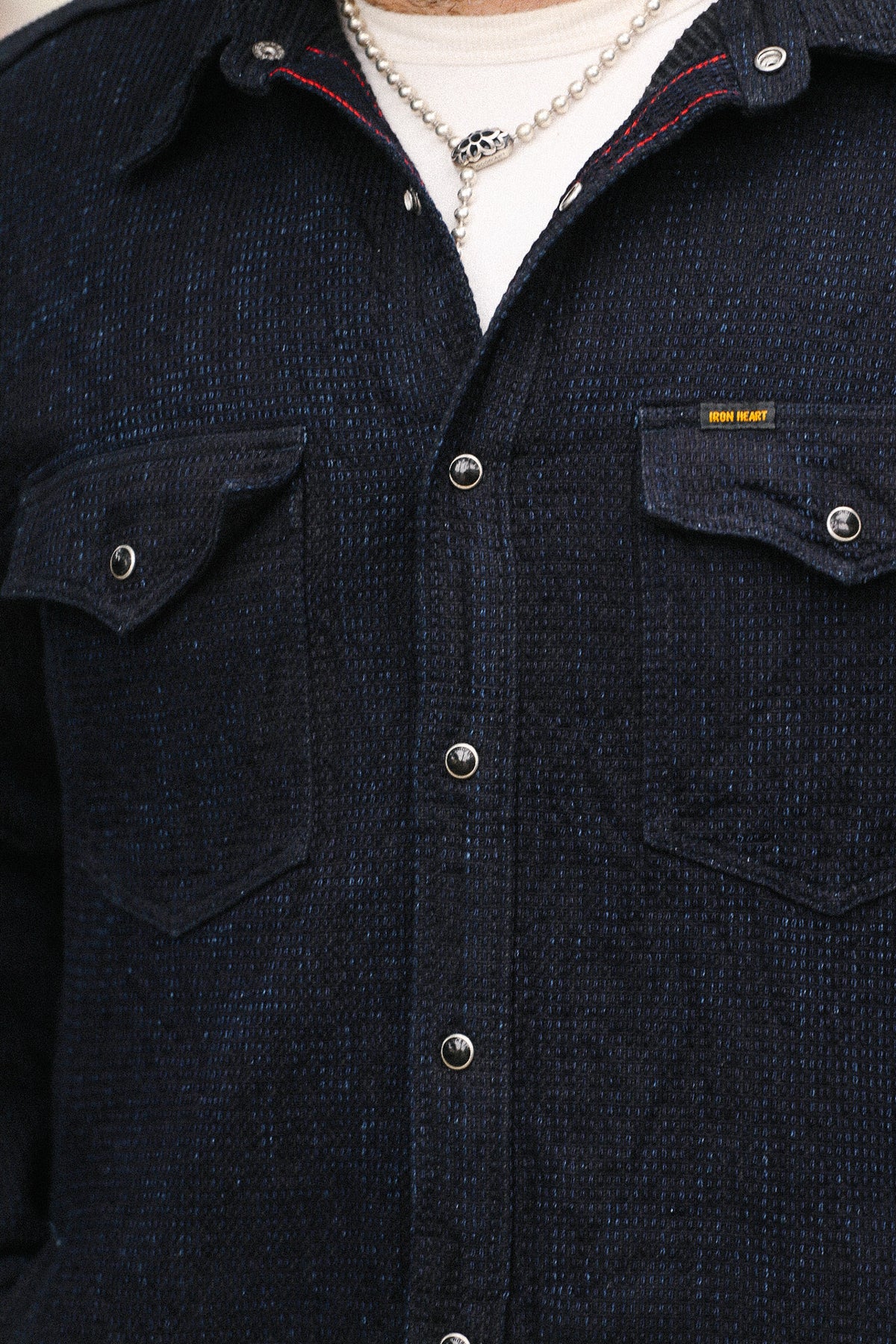 Dark denim shirt with button details and a visible brand label.