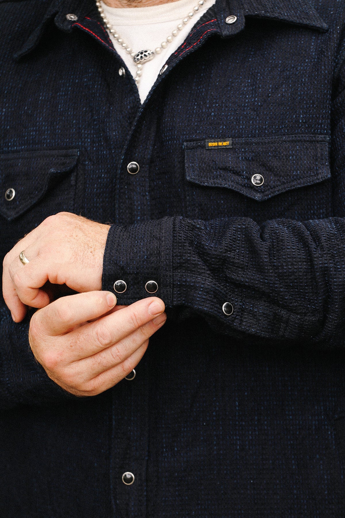 Close-up of a person wearing a dark denim jacket with visible buttons.