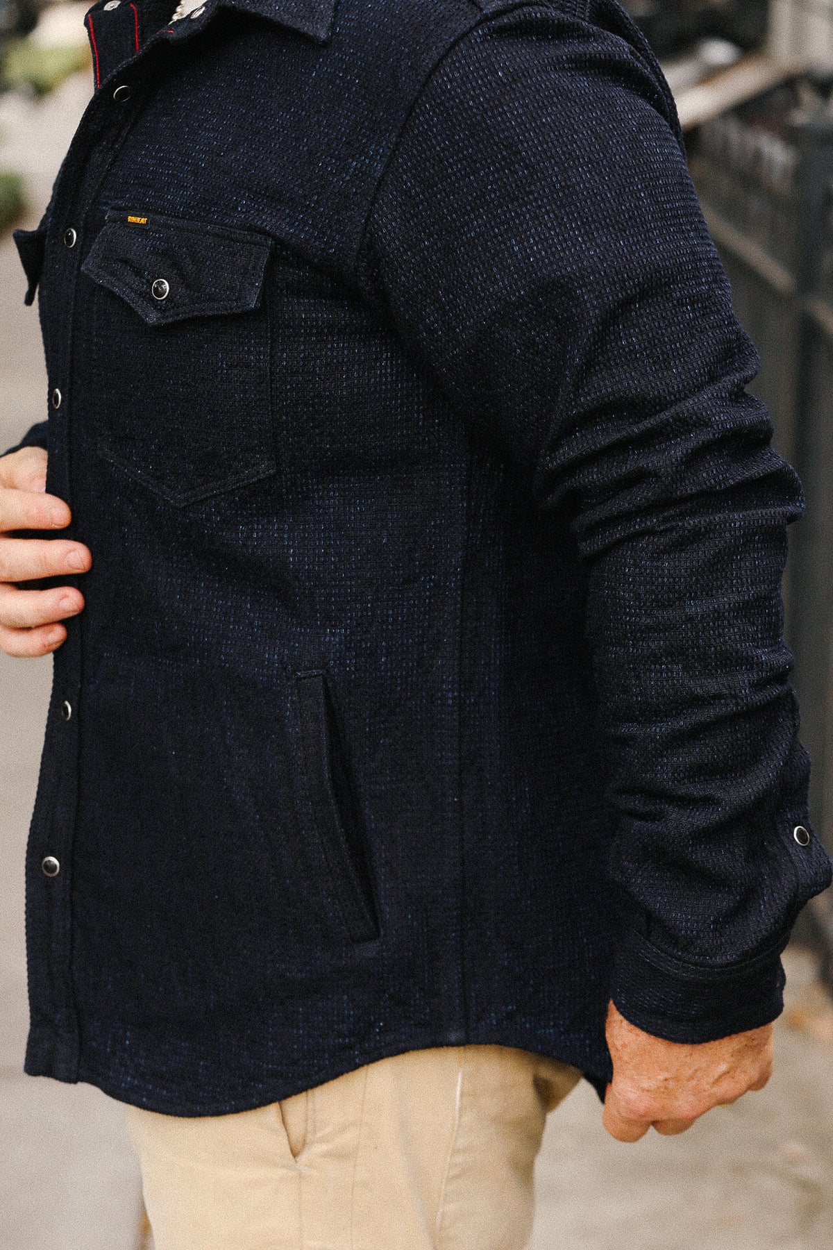 Person wearing a dark blue jacket with a blurred background