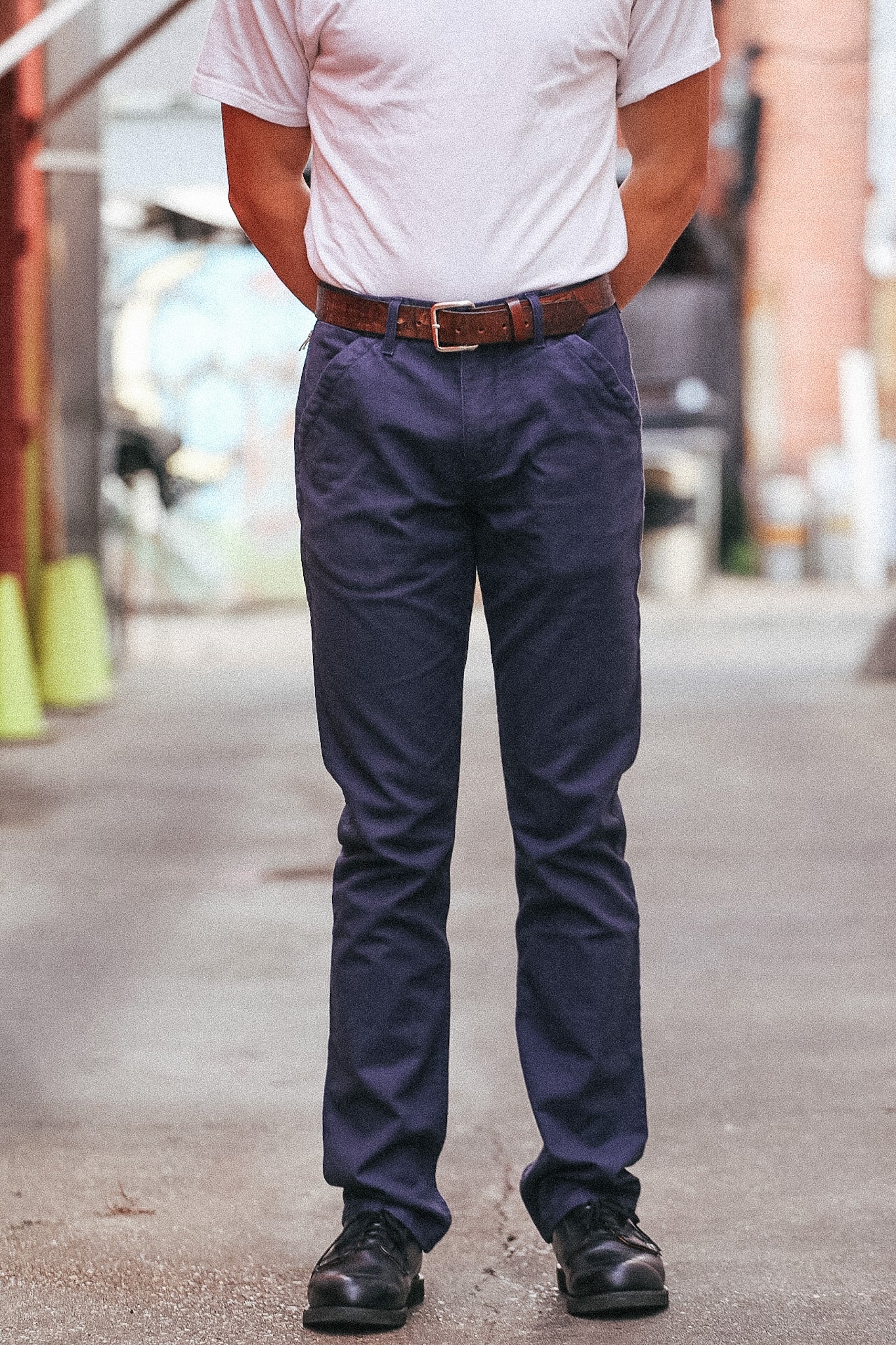 Person wearing navy pants and a white shirt with a blurred background