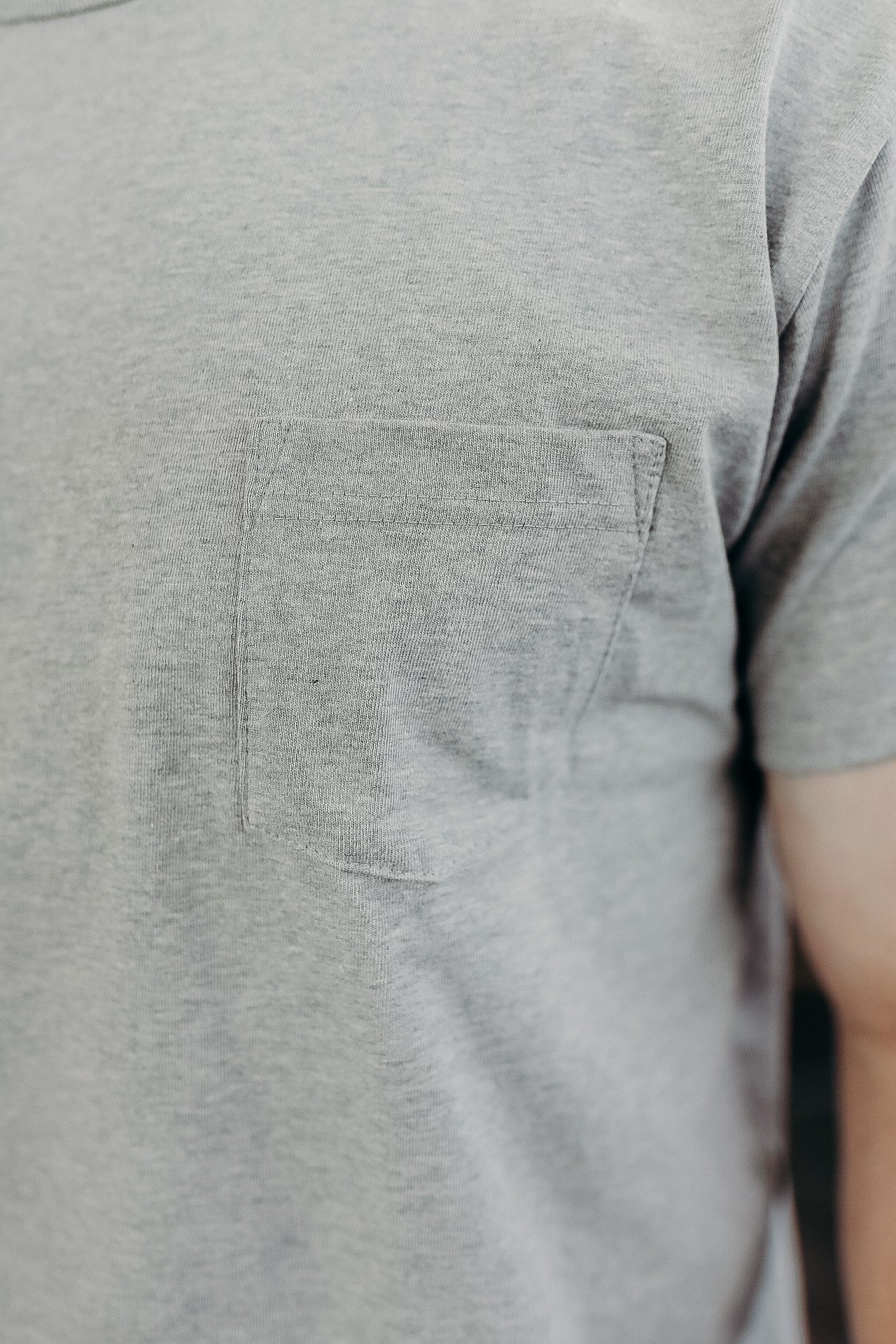 Close-up of a light gray soft cotton t-shirt with a stitched chest pocket, casual wearable fabric