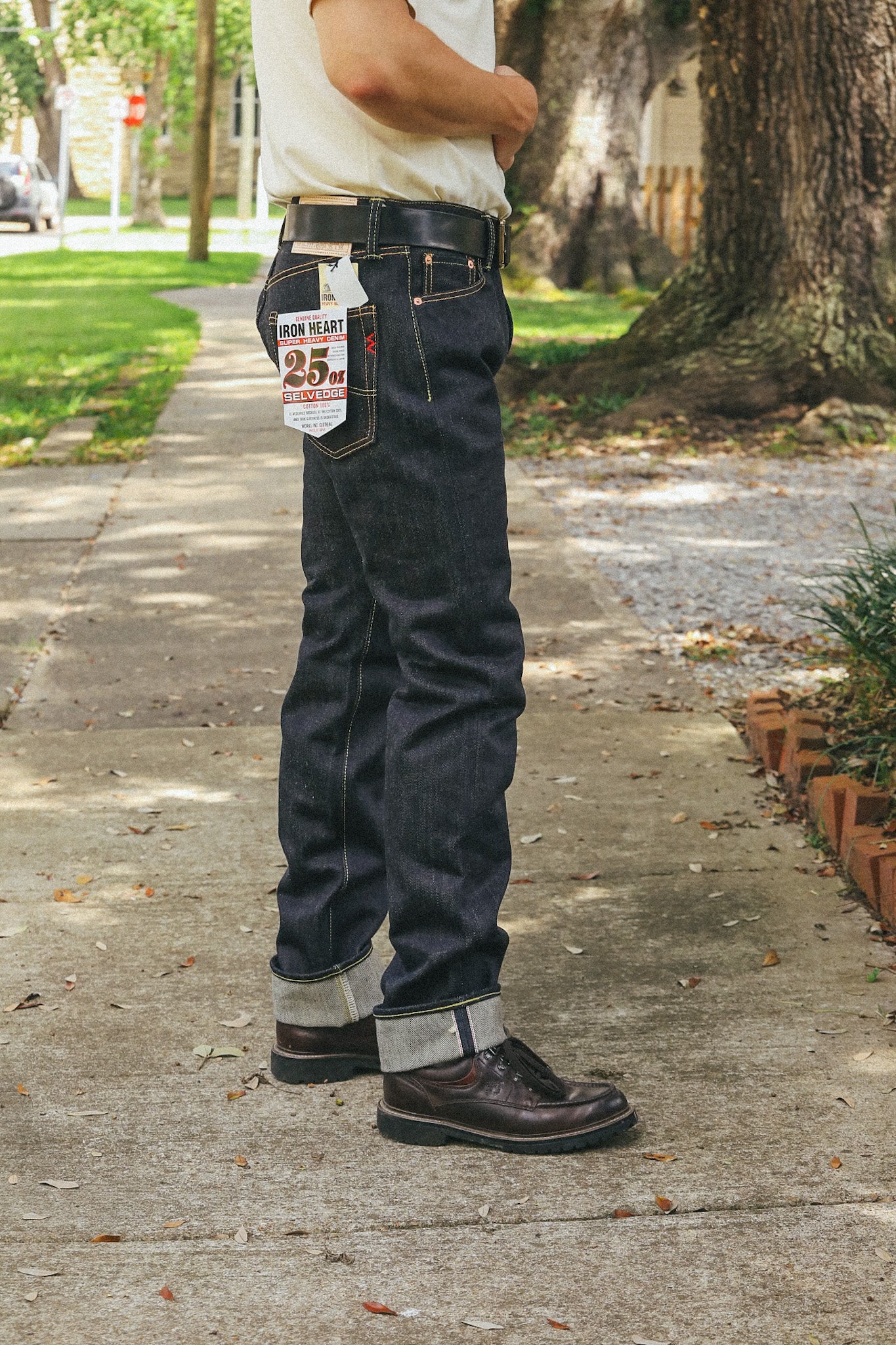 Man wearing dark blue Iron Heart 25oz selvage denim jeans with black belt and brown leather boots outdoors