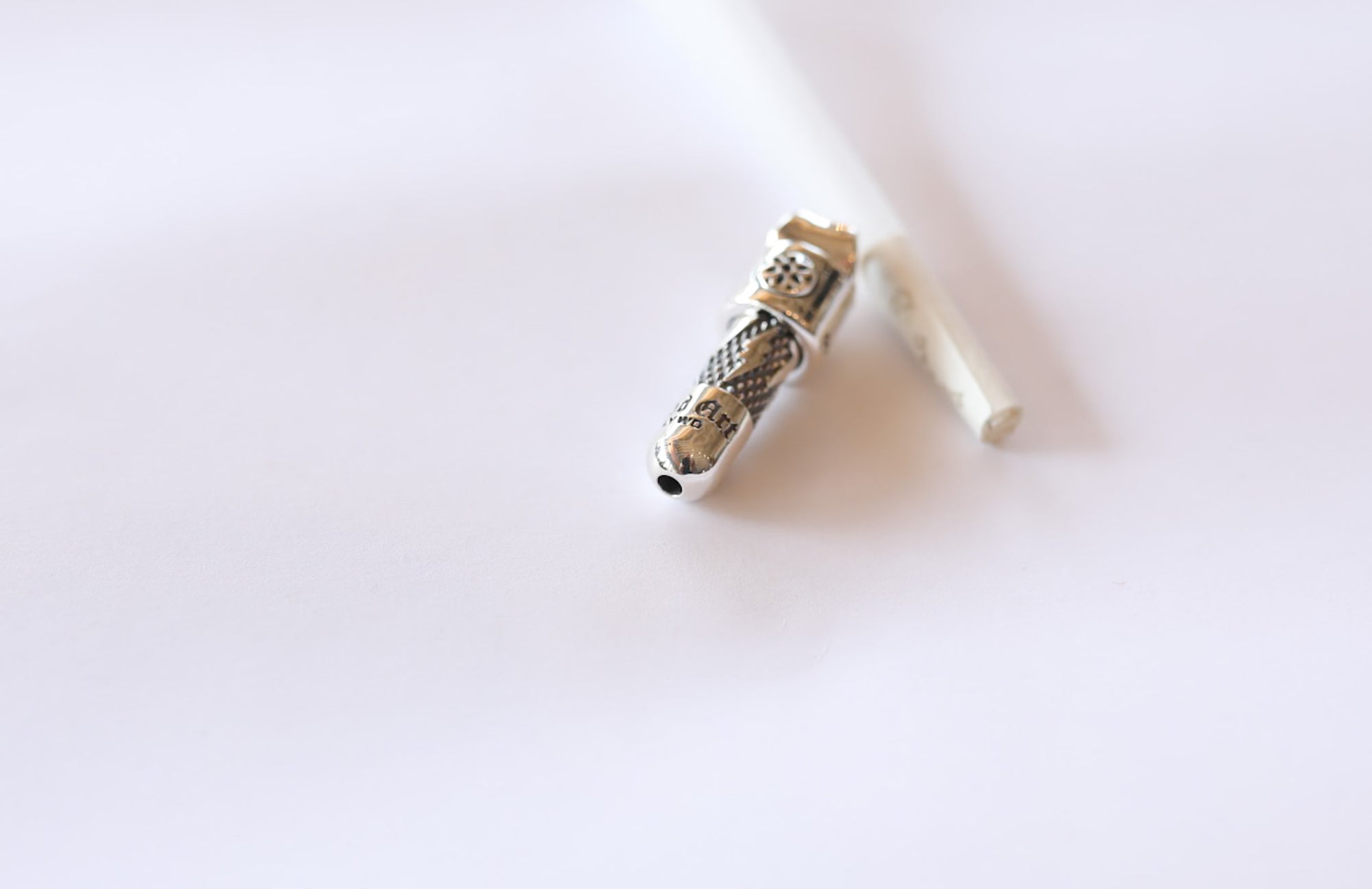 Close-up of a silver metallic smoking pipe with intricate design on white background