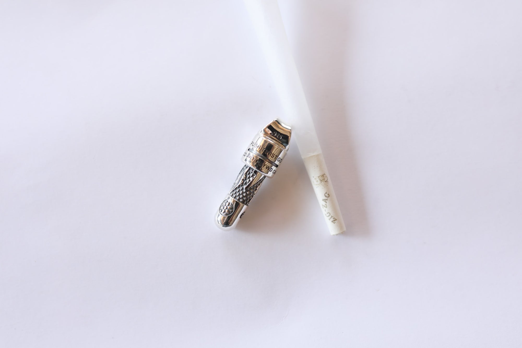 close-up of a silver finger armor ring and a white rolled paper on a white background
