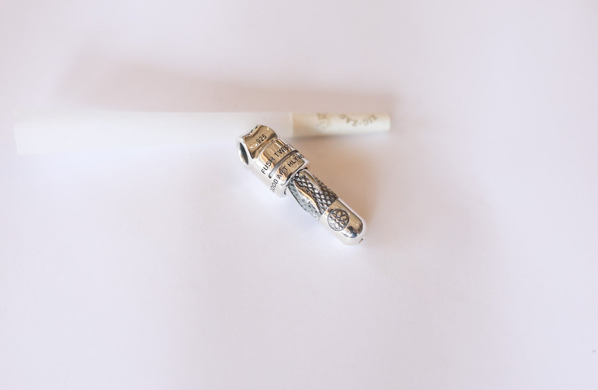 Sterling silver pipe with intricate textured design on white background