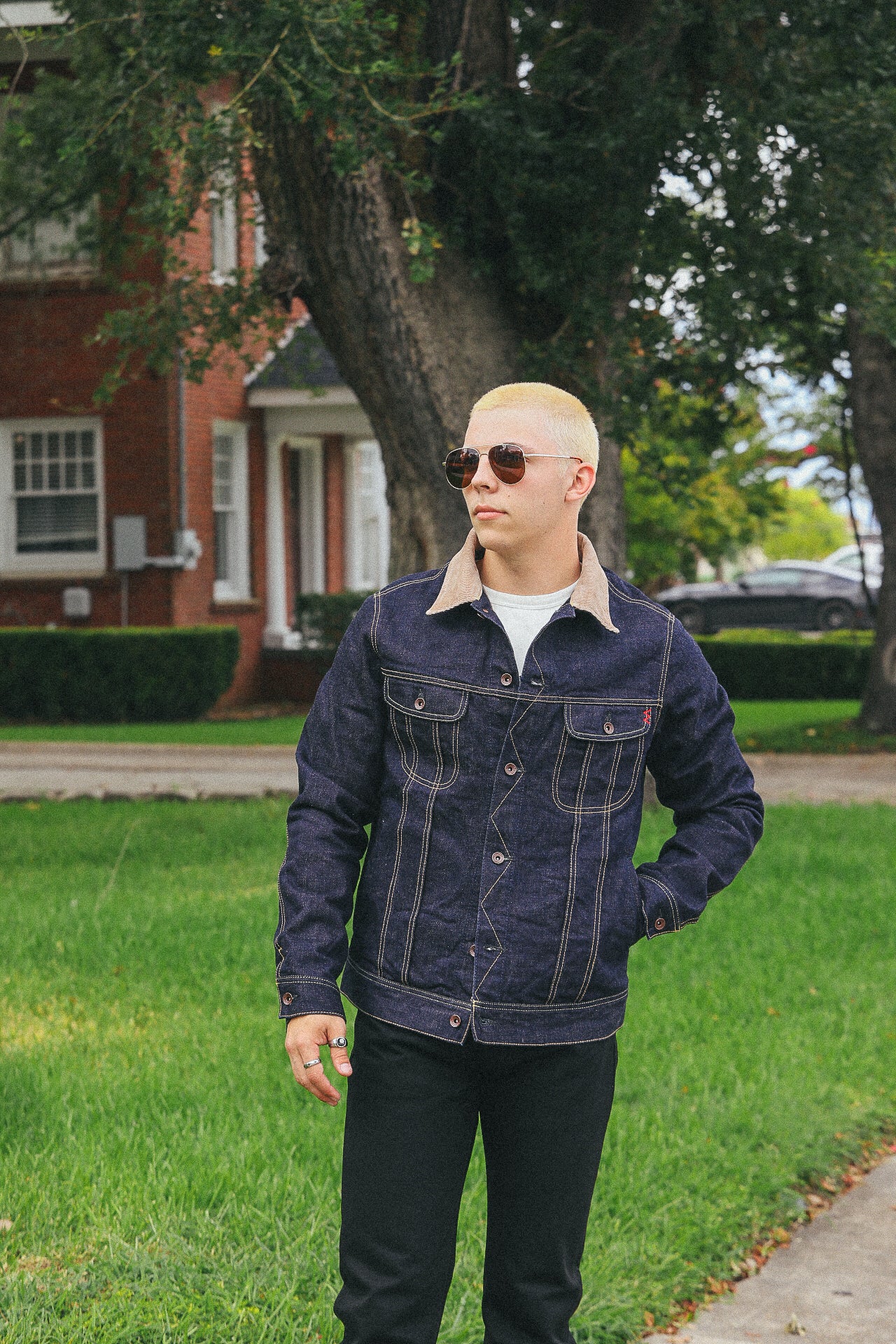 Young man wearing Iron Shop Provisions denim jacket with tan collar and sunglasses outdoors