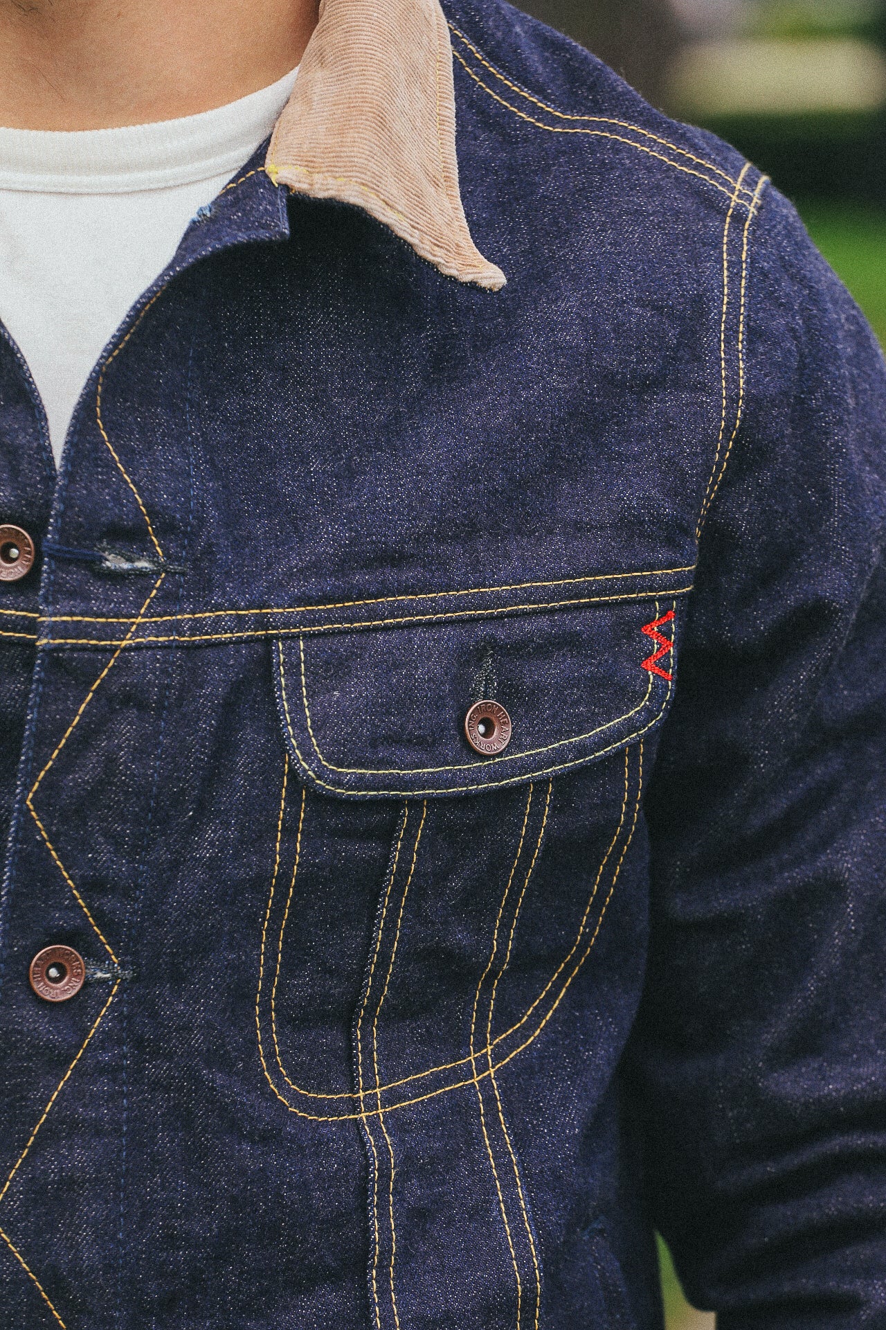 Close-up of denim jacket pocket with tan corduroy collar and contrasting yellow stitching from Iron Shop Provisions