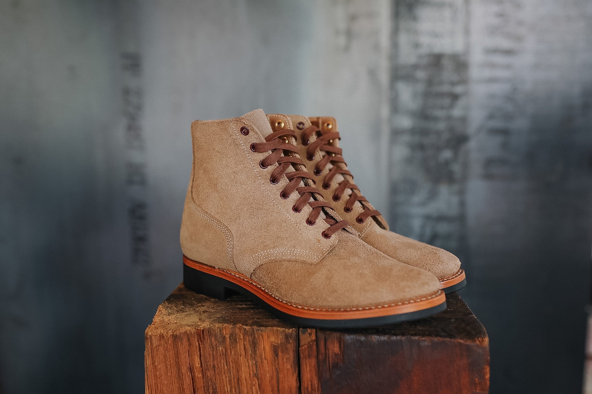 Pair of tan suede boots on a wooden block with a blurred background