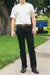 Man wearing white t-shirt, black jeans, brown leather belt, and black boots standing on sidewalk