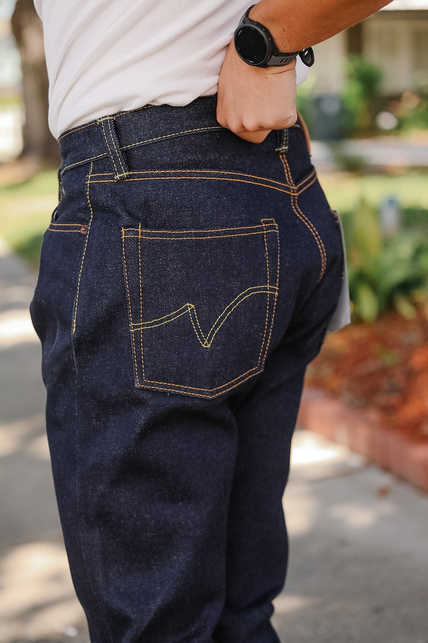 Person wearing dark blue jeans with a blurred outdoor background