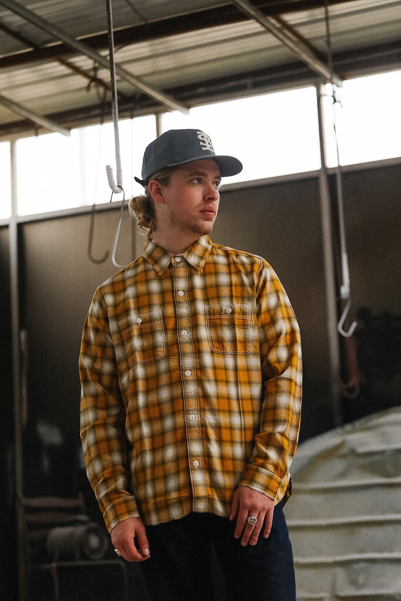 Person wearing a yellow plaid shirt and cap in an indoor setting