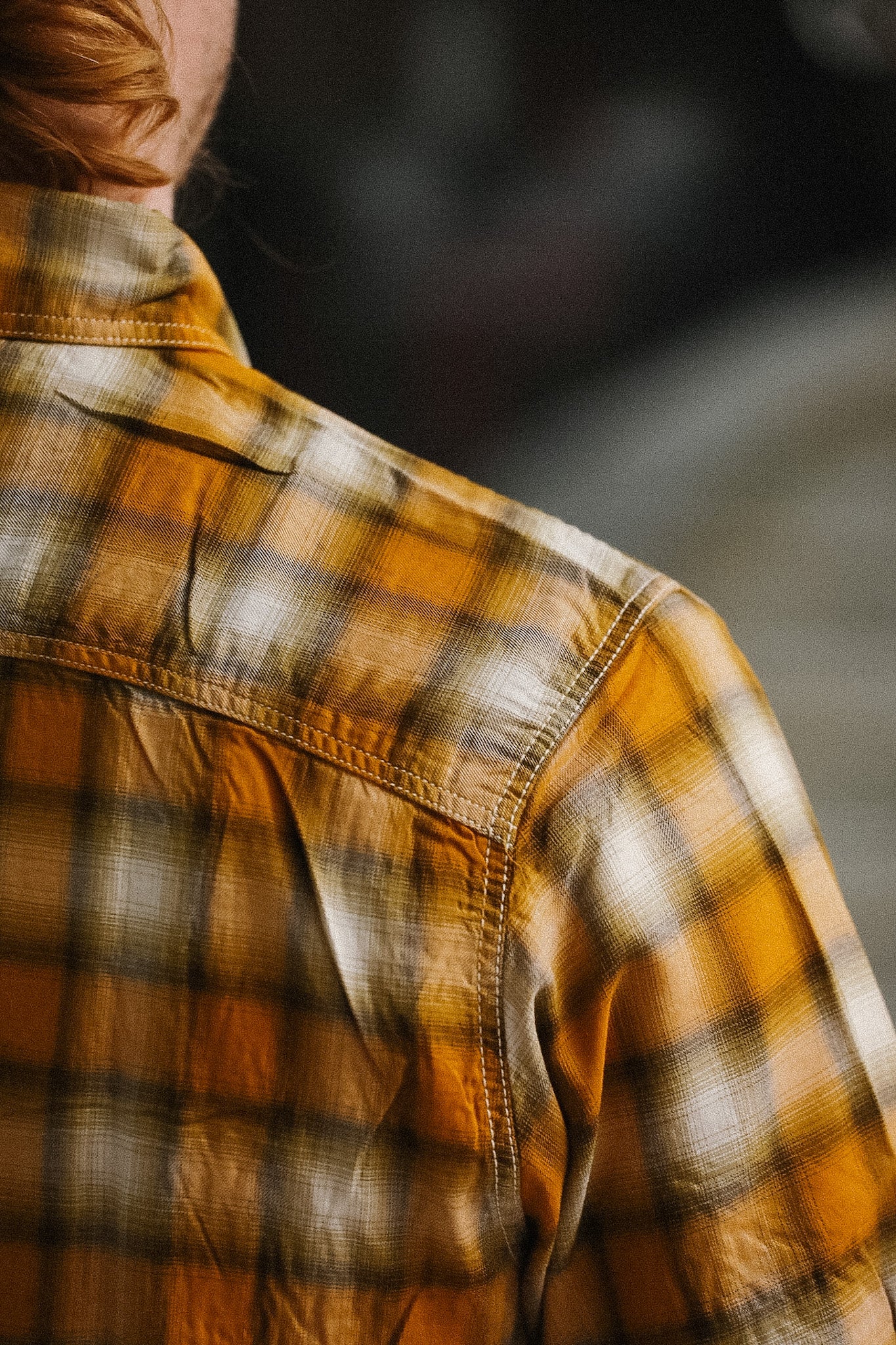 Person wearing a plaid shirt with a blurred background