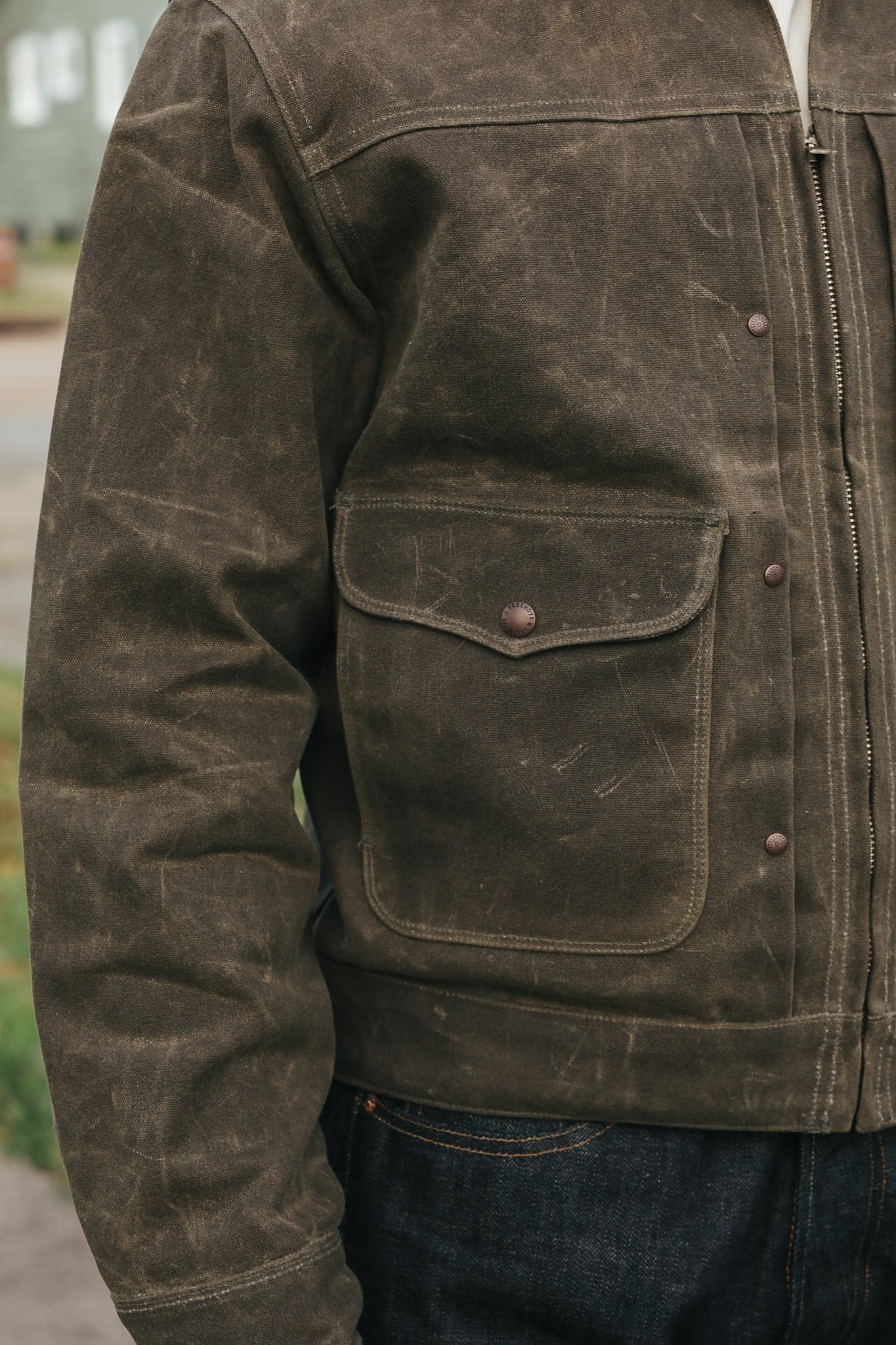 Close-up of a worn brown leather jacket with visible wear and tear.