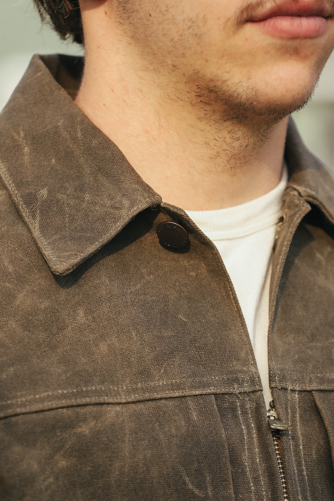 Close-up of a person wearing a brown leather jacket with a blurred background