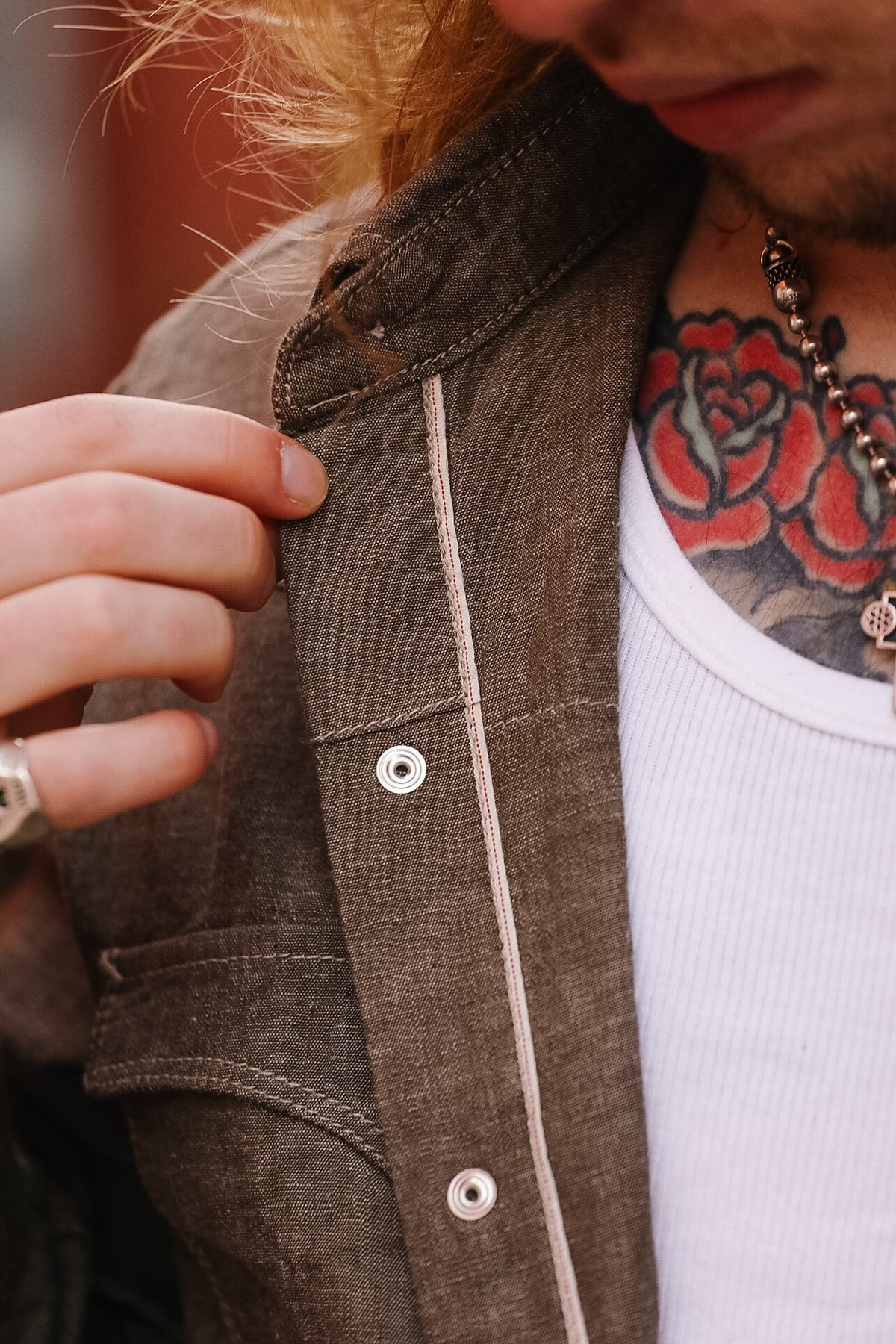 Close-up of a person wearing a brown jacket with a white shirt underneath, focusing on the collar and buttons.
