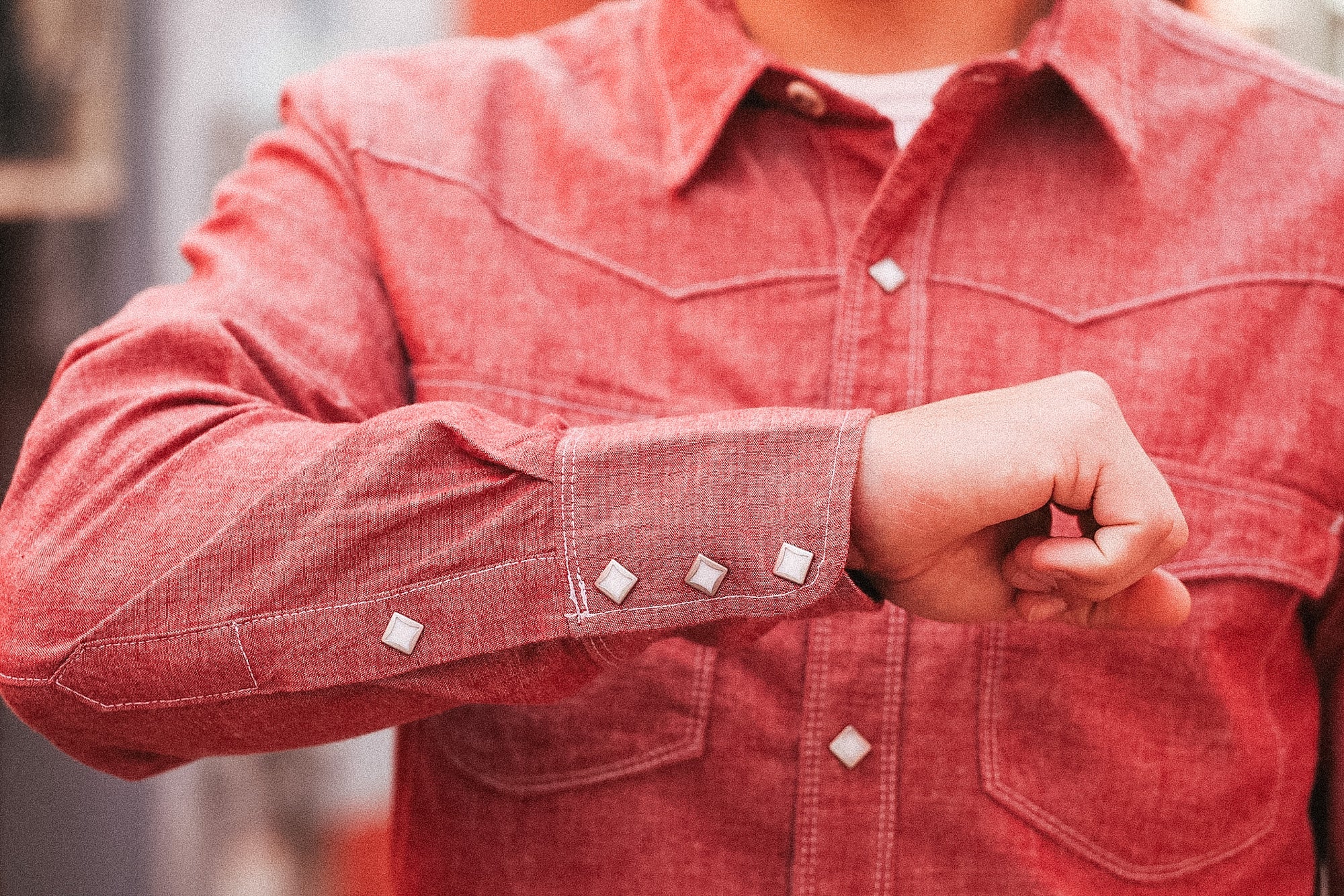 Red denim shirt with button details on a blurred background