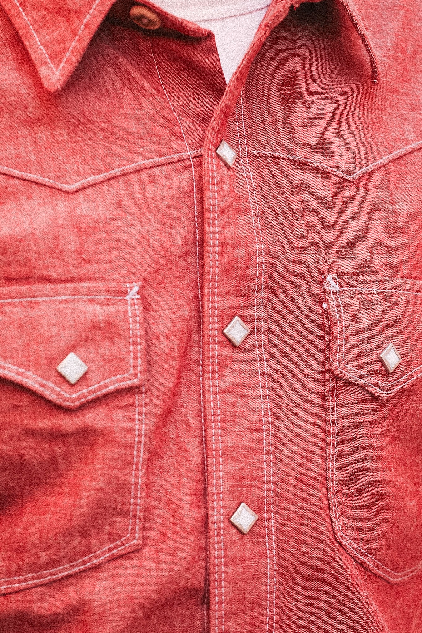Close-up of a red denim shirt with buttons and stitching details.
