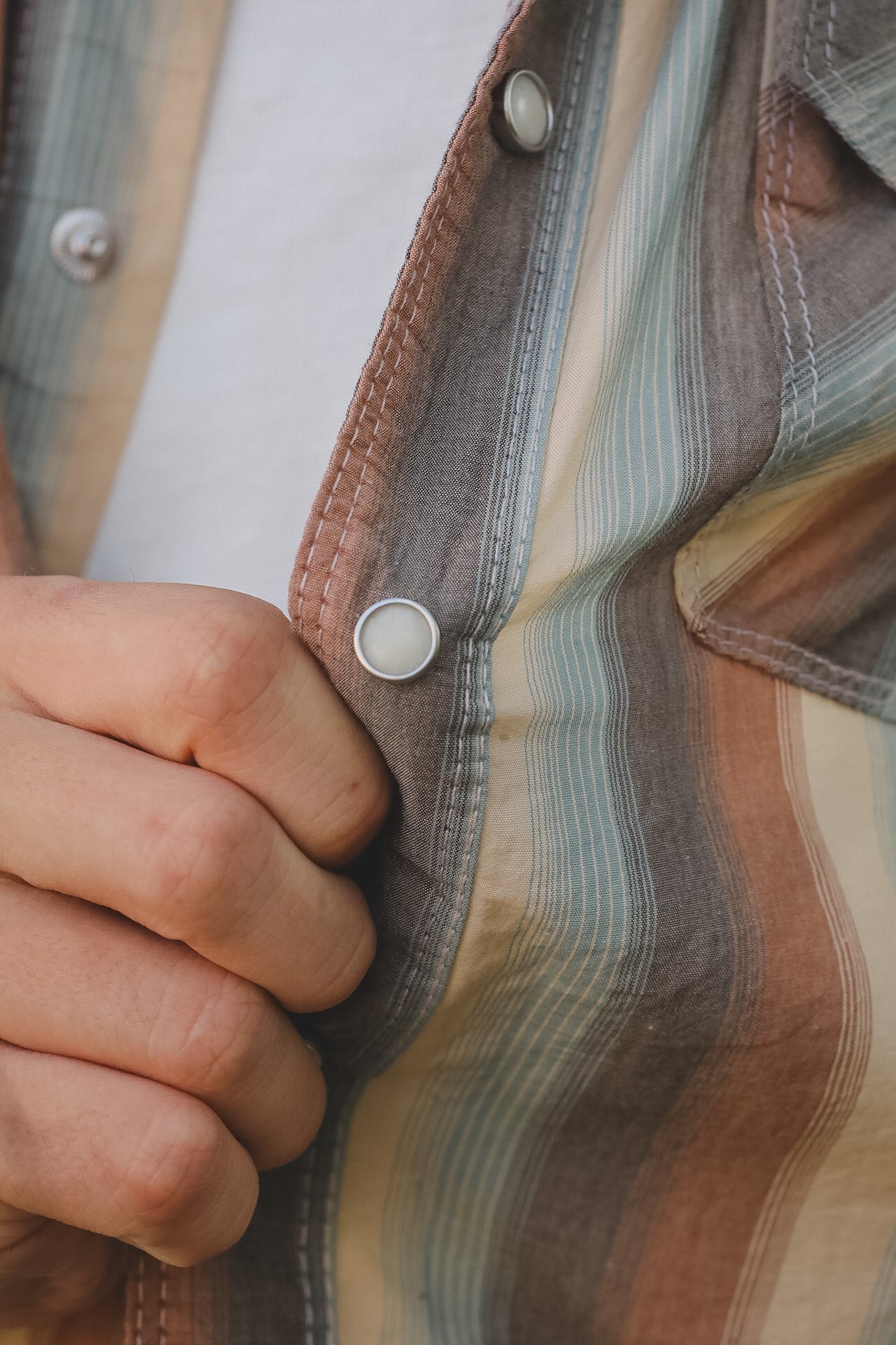 Close-up of a hand holding a striped fabric with visible buttons.