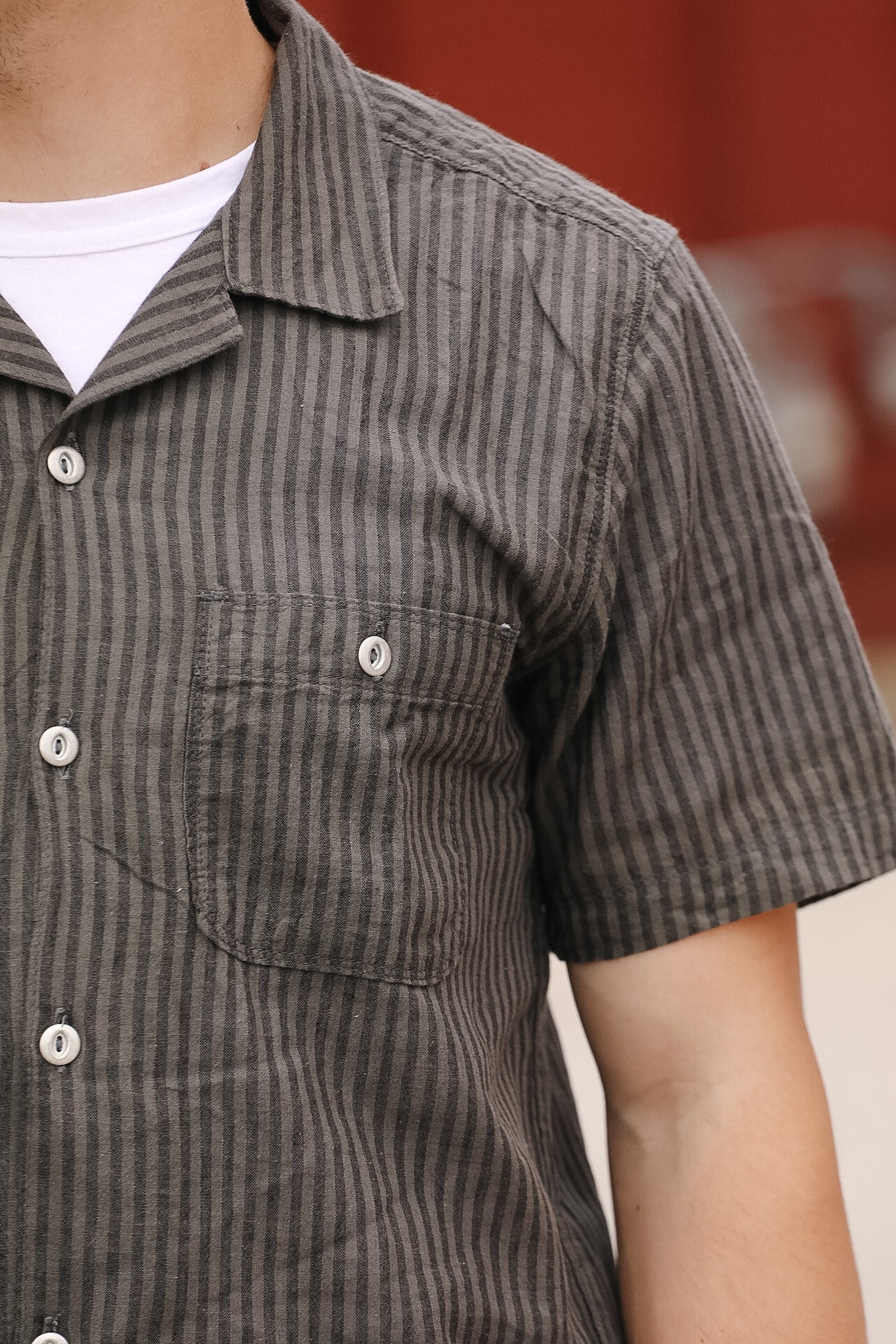 Close-up of a person wearing a brown striped shirt with a blurred background