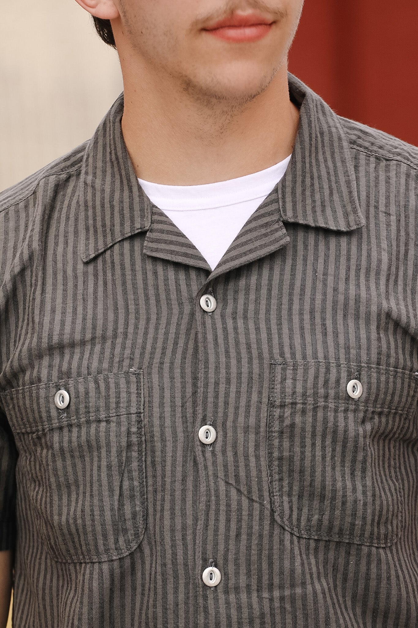 Close-up of a person wearing a gray striped shirt with a white collar.